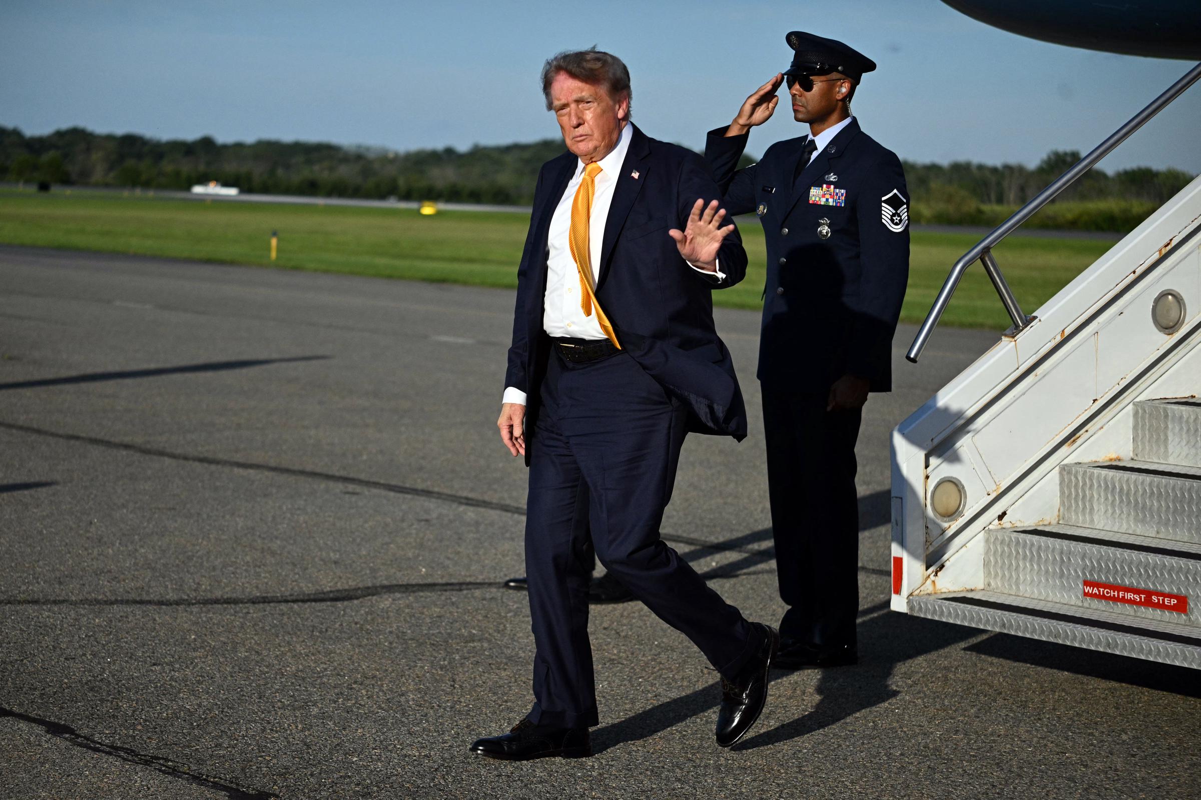 Trump waves to reporters at Morristown Municipal Airport, offering another view of the deeper brunette tones running through his familiar swept hairstyle.