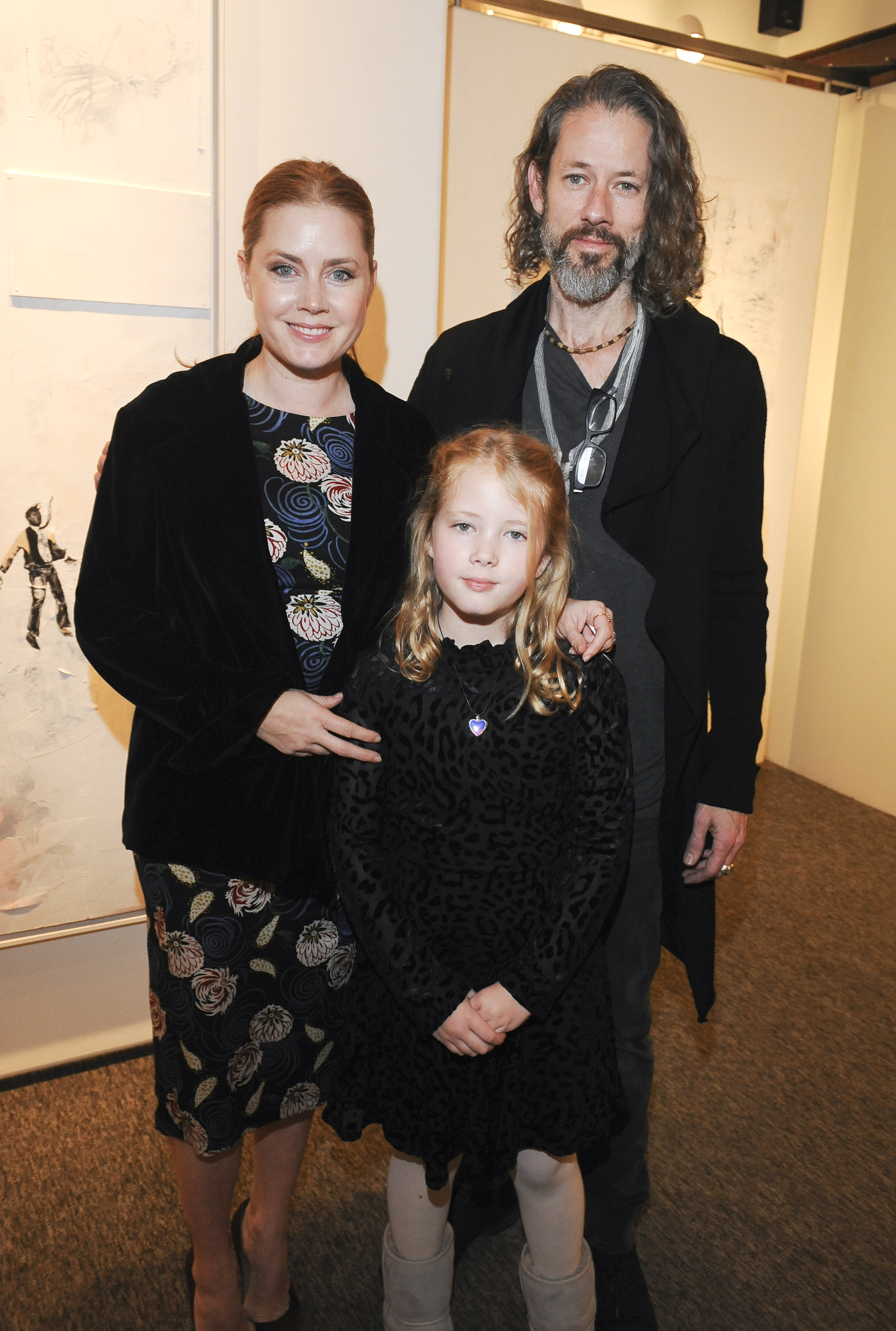 Amy Adams and Darren Le Gallo pose with their daughter, Aviana Olea Le Gallo, at an art event celebrating Darren's exhibition. The family stands closely together as they attend the gallery presentation.