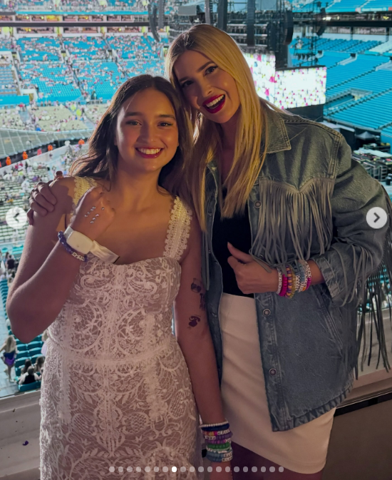 Posing from an arena suite overlooking a stadium crowd, Arabella and Ivanka celebrated together during a festive concert night. Arabella stood in a white lace dress stacked with colorful beaded friendship bracelets, while Ivanka flashed a wide smile with bright red lipstick in a fringe denim jacket over a white skirt. | Source: Instagram/ivankatrump