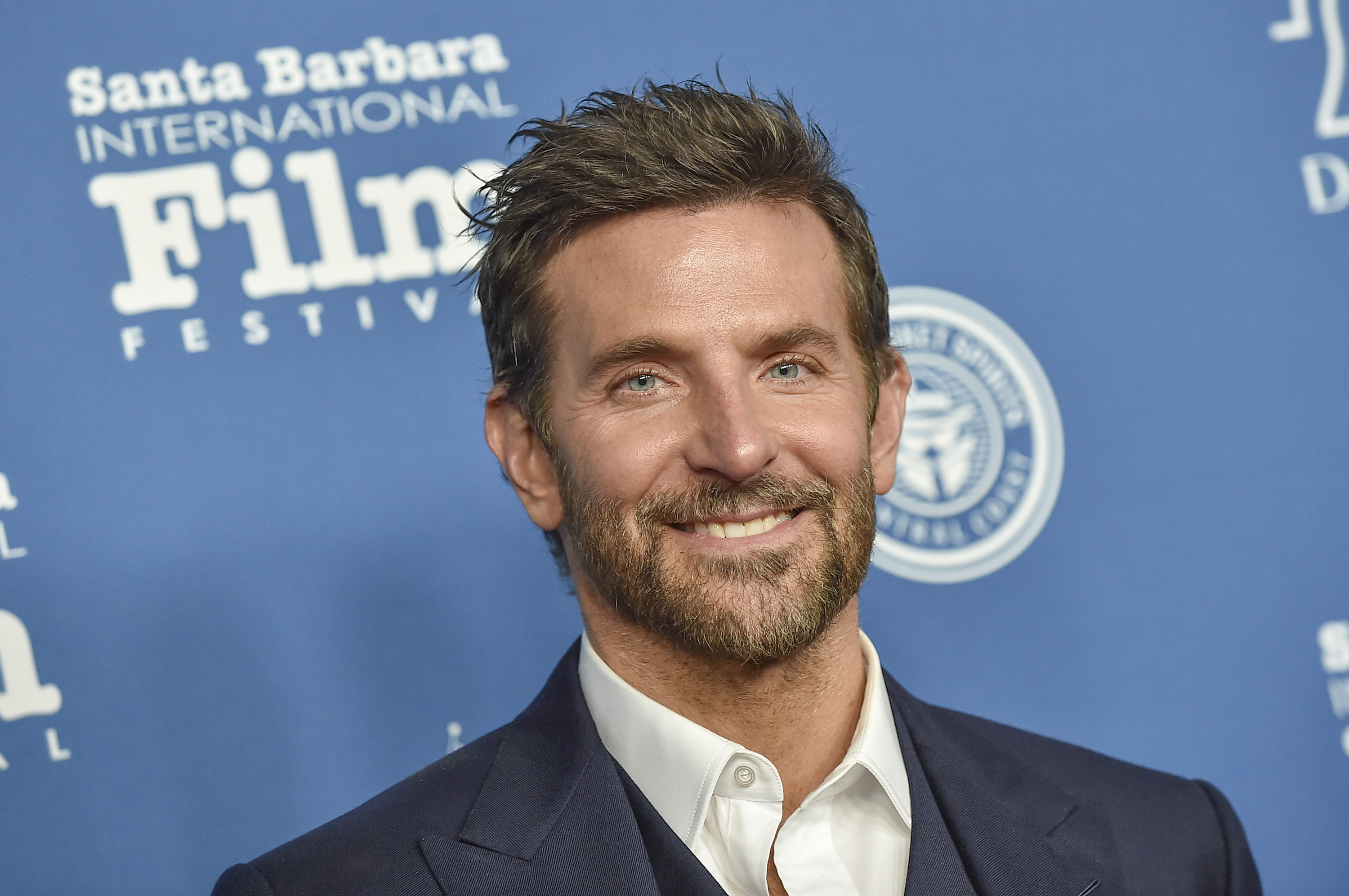 Cooper, now 49, displayed a warm, prominent smile with visible crow's feet around his bright blue eyes, and had a full, salt-and-pepper beard. His hair was short, dark brown, and styled in a slightly tousled quiff as he attended the Santa Barbara International Film Festival Outstanding Performer of the Year Award honoring Bradley Cooper held at The Arlington Theatre on February 8, 2024, in Santa Barbara, California.