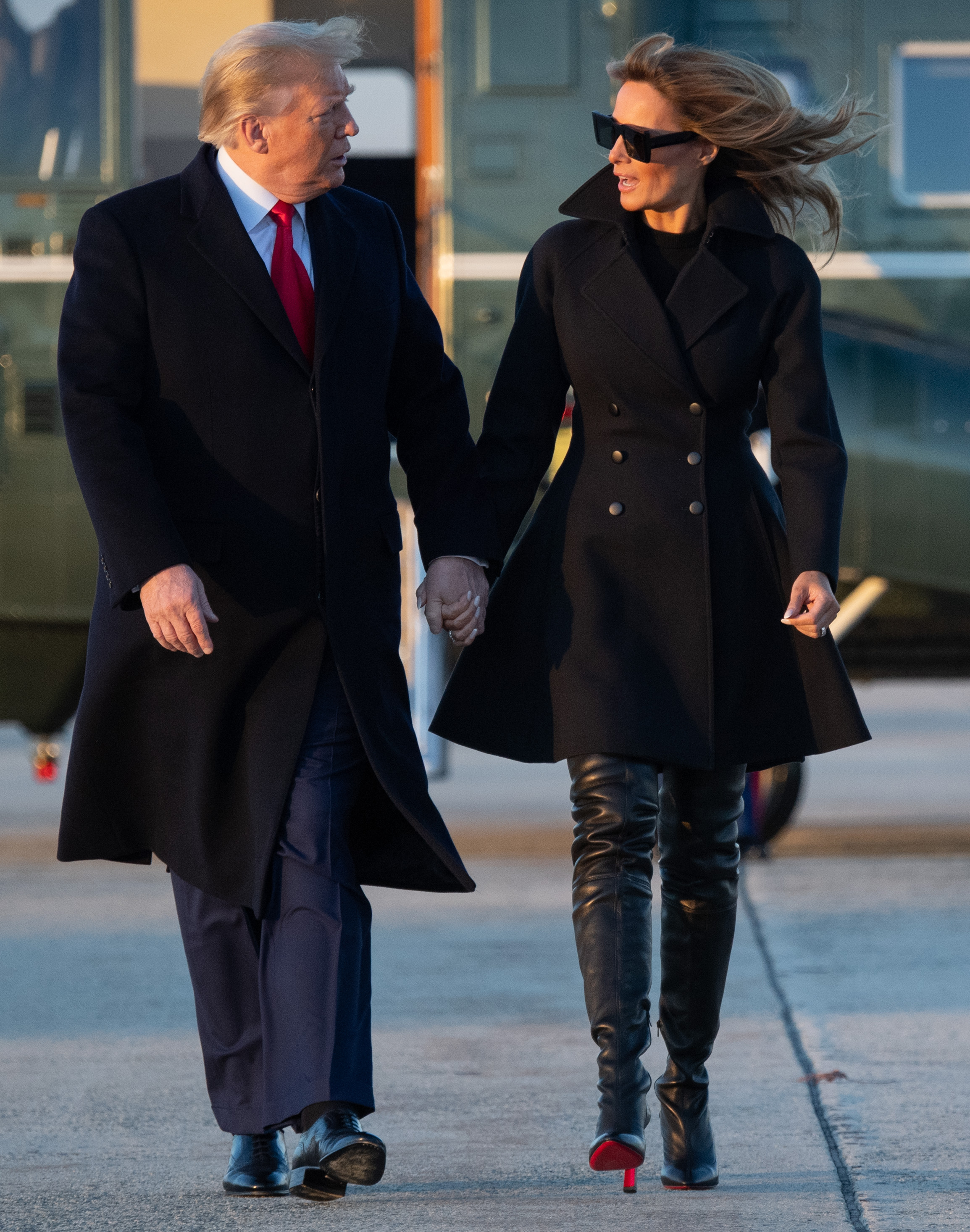 First Lady Melania Trump departs Joint Base Andrews in Maryland on December 23, 2020, to spend Christmas and New Year's at Mar-a-Lago, wearing an all-black double-breasted coat paired with Christian Louboutin thigh-high black leather stiletto boots featuring sky-high heels and flashes of signature red soles.