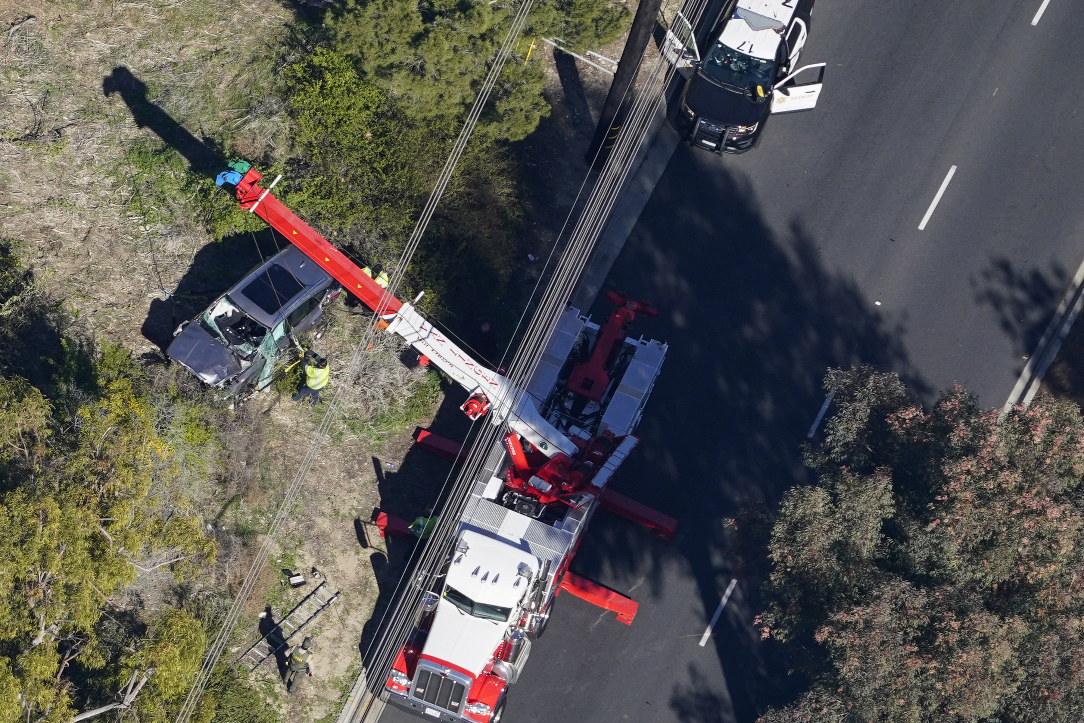 Workers move a vehicle after a rollover accident involving golfer Tiger Woods in Rancho Palos Verdes, California on February 23, 2021.