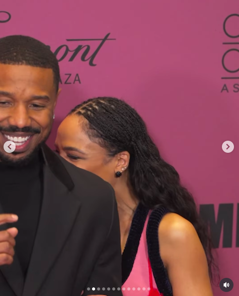 Tessa Thompson hiding behind Michael B. Jordan as she giggles. | Source: Instagram/people
