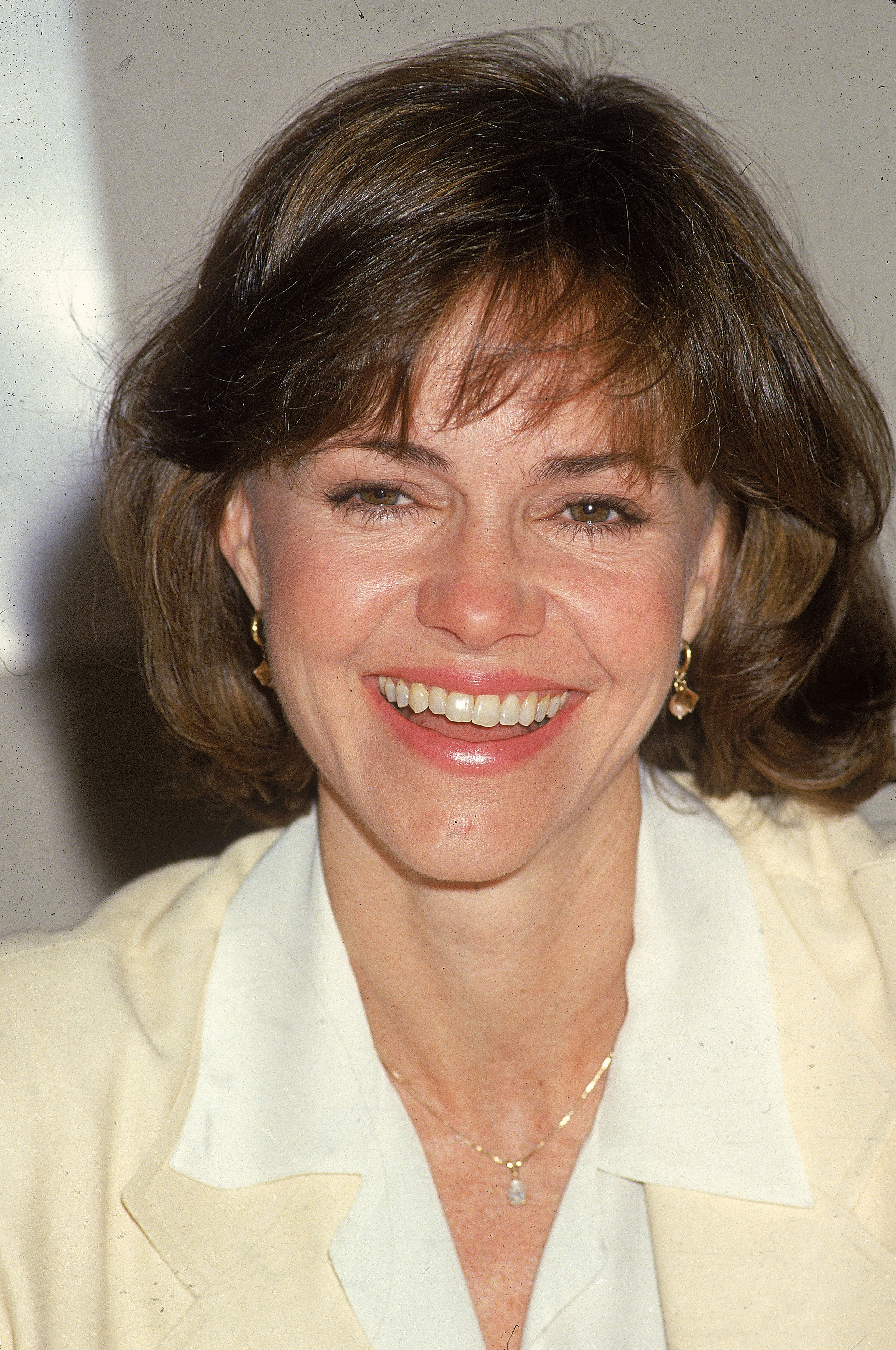 Sally Field, wearing nude lipstick that complements her skin tone, is captured mid-laughter in a striking headshot. In her mid 40s, the fine lines near her eyes and the definition of her cheekbones are visible, yet her beauty remains as magnificent as ever.