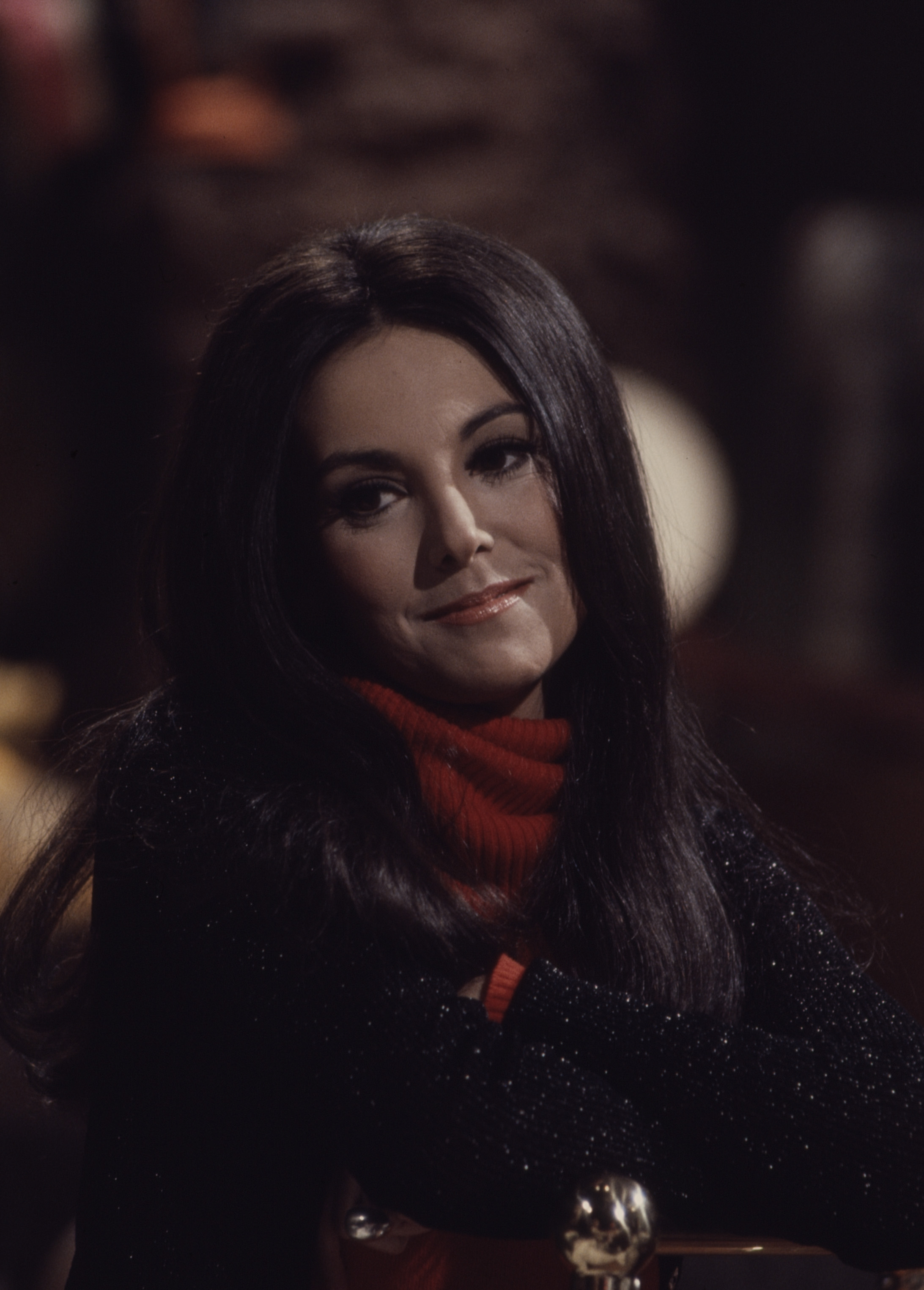 Marlo Thomas appears thoughtful in a dimly lit scene from the ABC television special "Acts of Love and Other Comedies," wearing a striking red turtleneck beneath a dark coat. | Source: Getty Images
