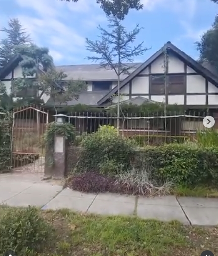 In a post dated July 29, 2026, the Los Angeles home where Marvin Gaye's life came to a tragic end is pictured from the sidewalk, its Tudor-style facade rising behind a metal fence and layers of greenery. Dark timber detailing traces the light exterior, while steep gables, mature trees, and an enclosed front garden give the property a secluded appearance. | Source: Instagram/stephanosmoothlewis