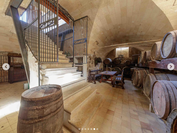 Rows of wooden barrels fill S'Estaca's vaulted wine cellar, where stone walls and an arched ceiling preserve a distinctly rustic atmosphere. The space complements the estate's vineyard, one of several features that make the property feel more like a private compound than a conventional vacation home. | Source: Instagram/robbreport