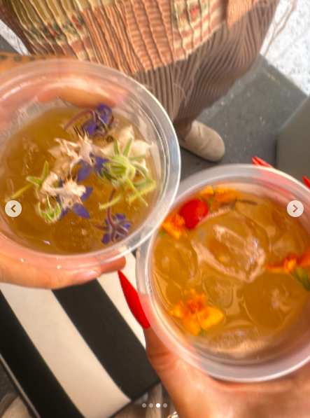 A close-up of two people holding onto drinks with edible flowers in them. | Source: Instagram/heidiklum