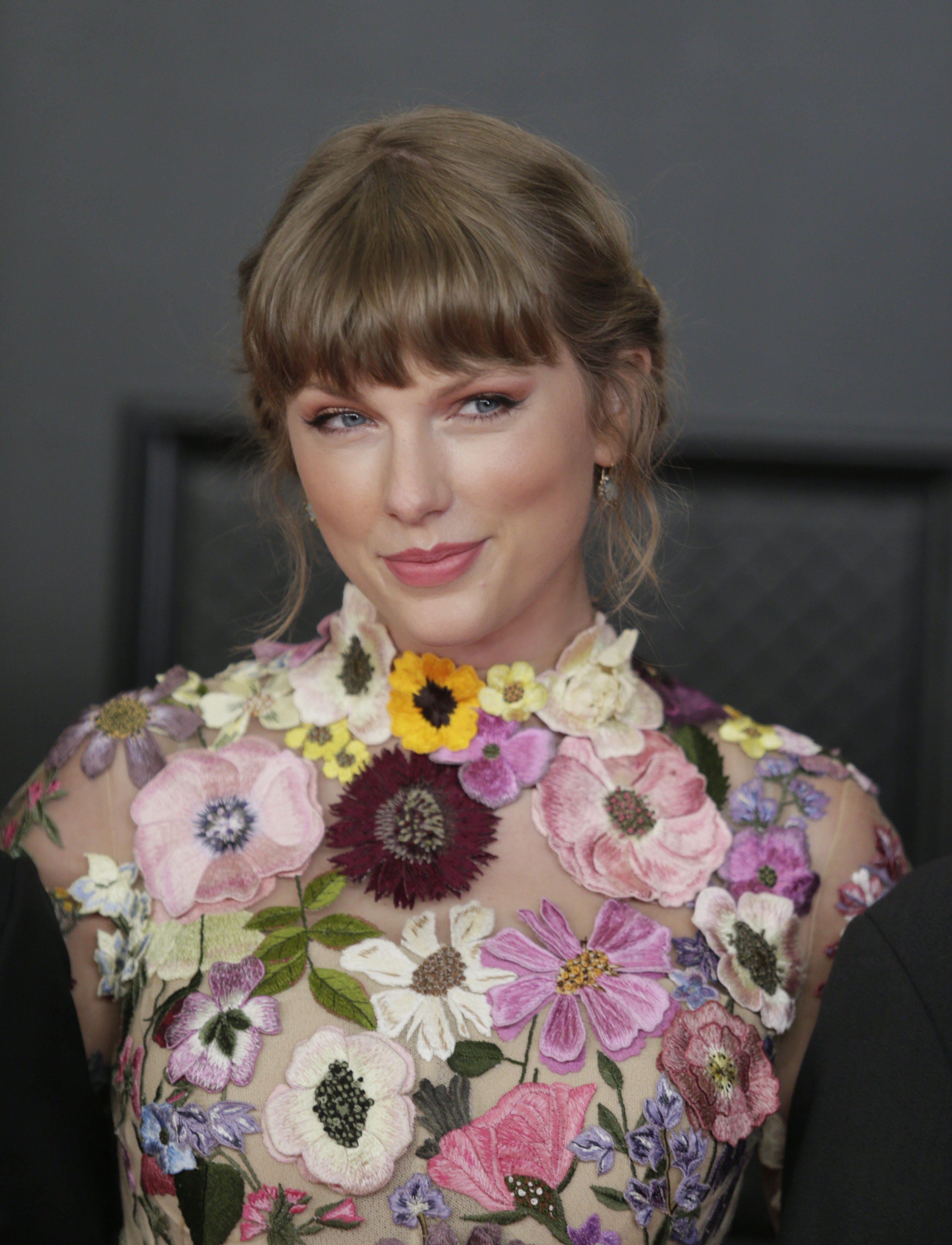 Taylor Swift attends the 63rd Annual Grammy Awards, broadcast live from the Staples Center in Los Angeles. She gives a slight smile, her hair styled in an elegant updo, and looks radiant in a flower-embroidered dress.