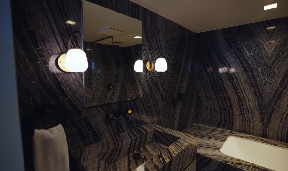 Christopher did not hide his pride in this bathroom, and its dramatic marble makes the enthusiasm understandable. Dark veining envelopes the room so completely that the stone becomes its own artwork. | Source: YouTube/Architectural Digest