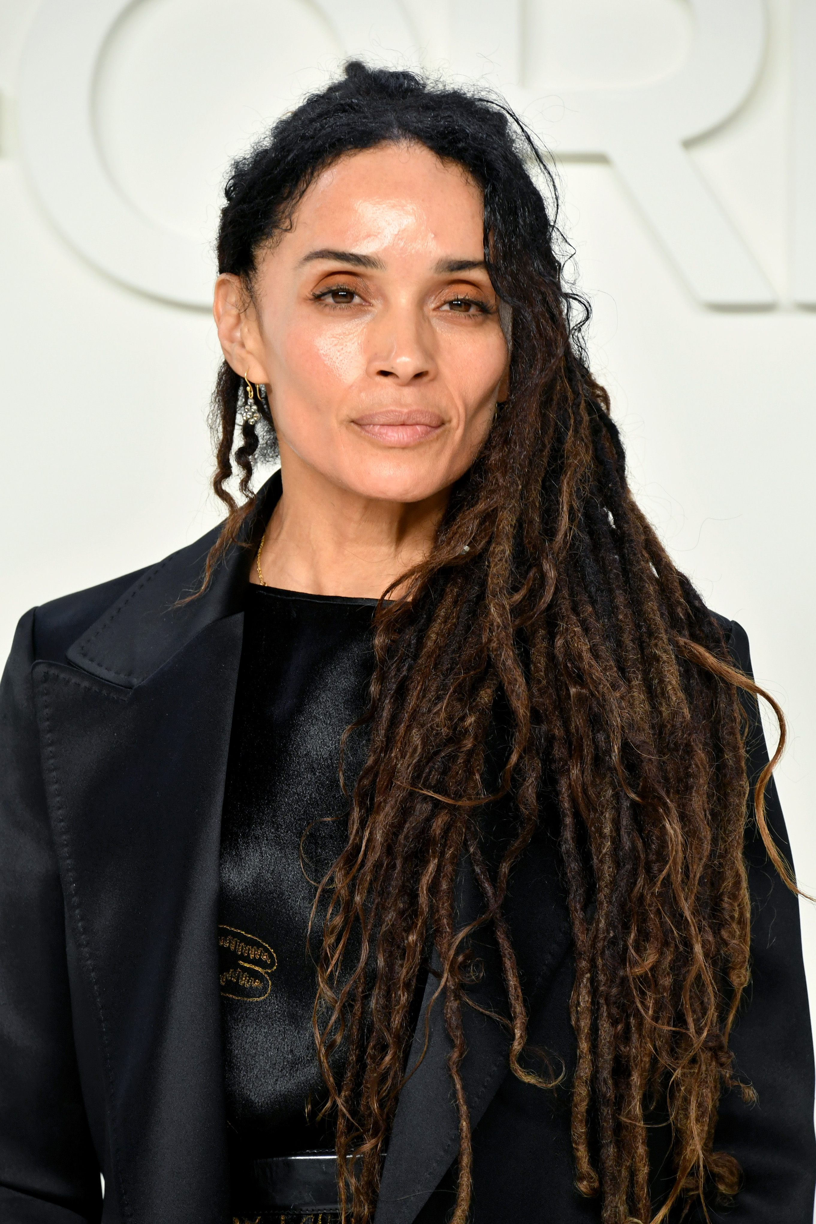 Lisa Bonet poses for photographers at the Tom Ford runway presentation in Hollywood, her long locs swept over one shoulder as she appears calm and composed.