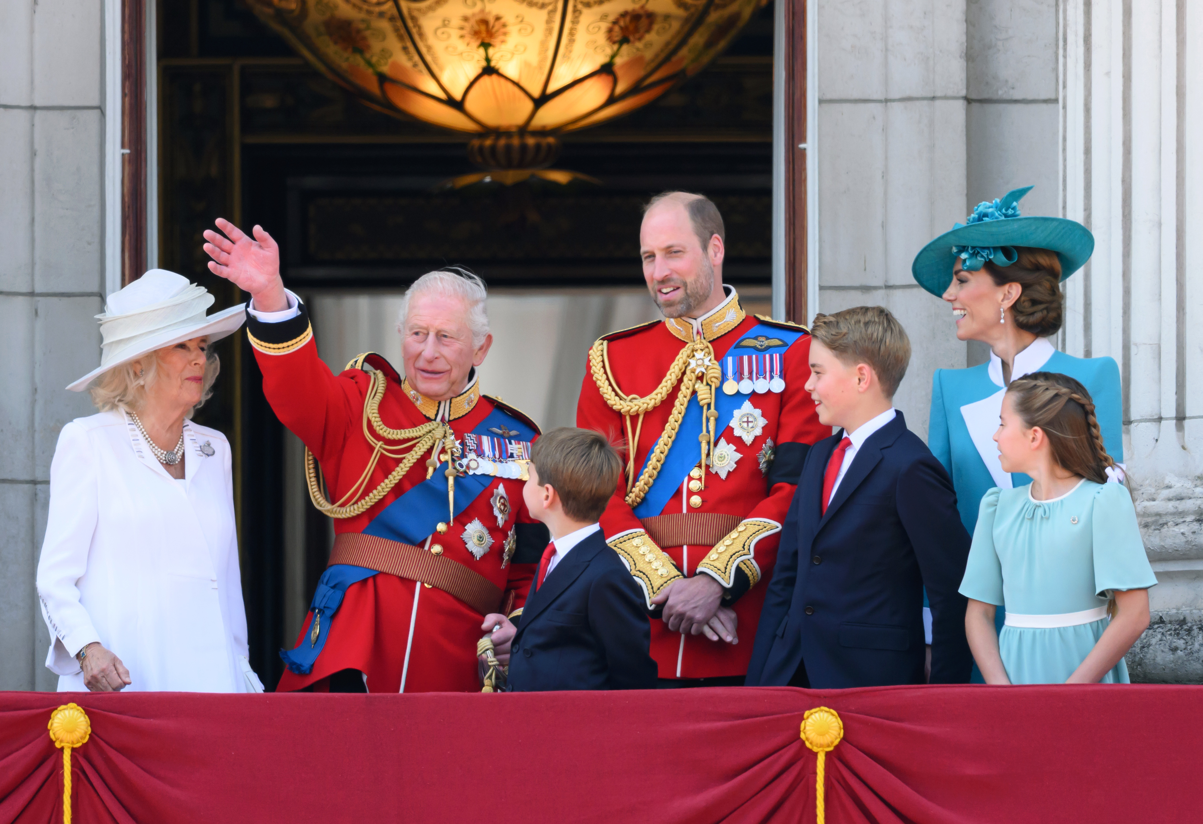 King Charles III waves to the people of England as Queen Camilla, Prince William, Princes Louis and George, and Princesses Catherine and Charlotte watch him on the balcony of Buckingham Palace.