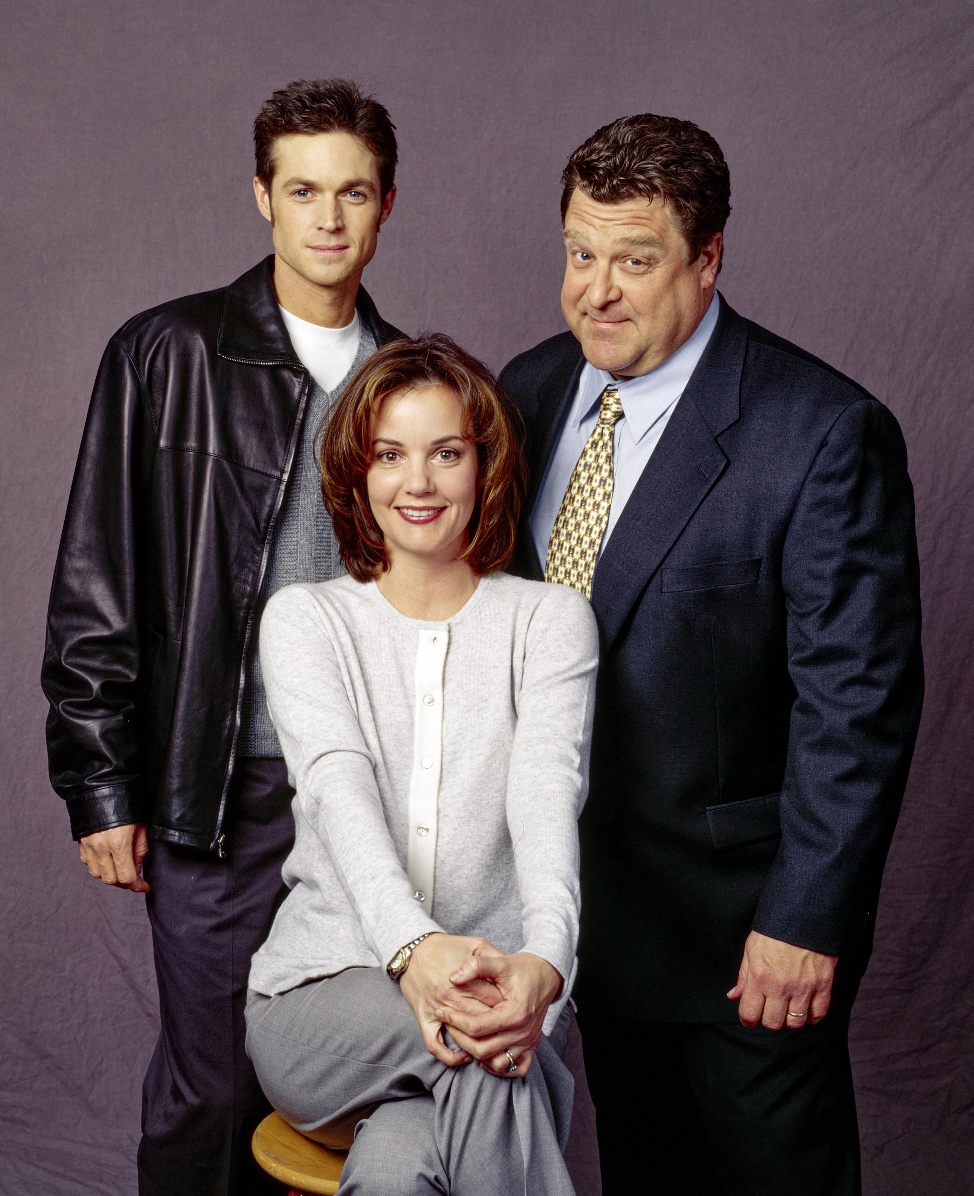 Goodman posed with Eric Close and Margaret Colin in a promotional portrait for the CBS science-fiction drama "Now and Again." Dressed in a dark suit and patterned tie, he appeared as Michael Wiseman in the series, adding another snapshot of his appearance around the end of the decade.