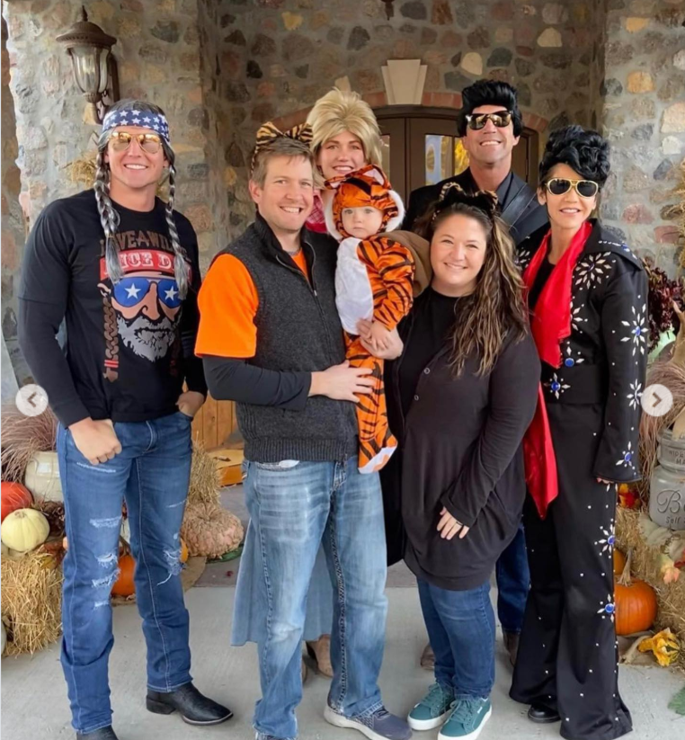 The cast expands outdoors as costumes and smiles collide—Elvis, Dolly, and a tiny tiger stealing attention at the center of a cheerful, family-filled scene. | Source: Instagram/sdbryonnoem