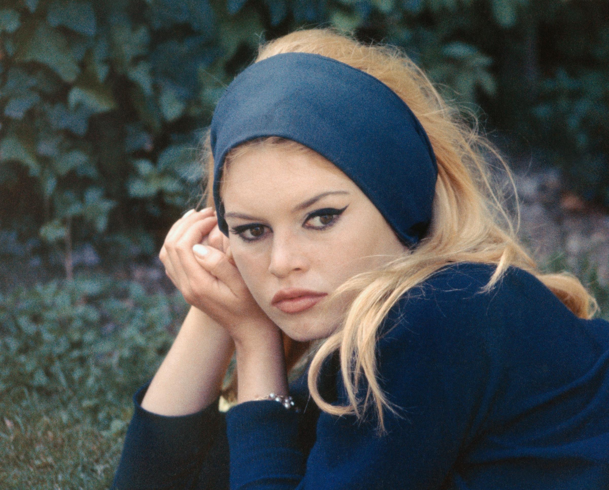 Brigitte Bardot is photographed on a film set, resting her head on her hands while looking toward the camera | Source: Getty Images