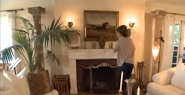 A white fireplace serves as a striking focal point, topped with a vintage equestrian painting. | Source: YouTube/@Biography