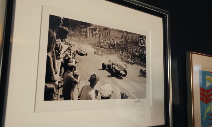 The vintage racing imagery fits the room's moody, nostalgic tone. It feels like part of Mark's personality has been built into the walls. | Source: YouTube/Architectural Digest