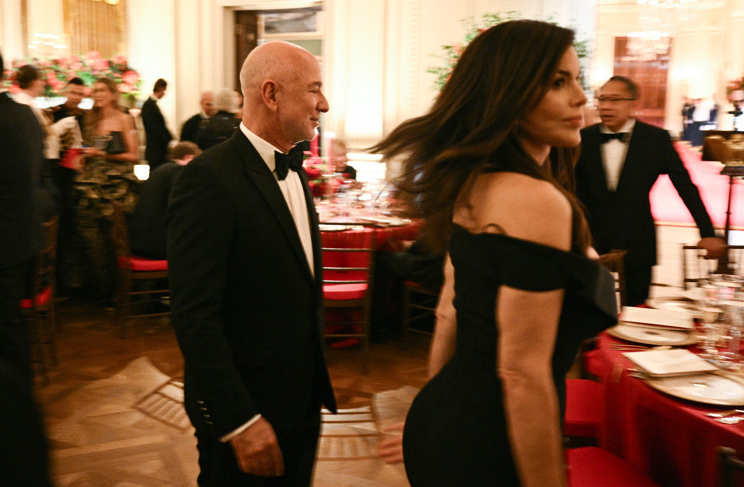Amazon founder Jeff Bezos and his wife Lauren Sánchez Bezos made a glamorous entrance into the East Room of the White House on September 24, 2026, in Washington, DC. Attending the lavish state dinner hosted by President Donald Trump for Chinese President Xi Jinping, Lauren turned heads in a vintage off-the-shoulder black Alexander McQueen dress, while Jeff complemented her in a sharp black tuxedo and bow tie amid banquet tables decorated with red linens and fine china. | Source: Getty Images