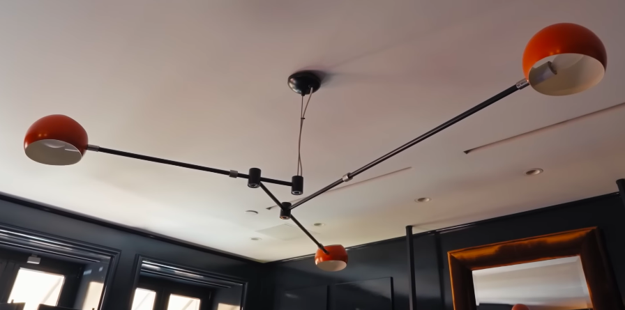 Even the ceiling fixture commits to the room's retro lounge mood. In this house, lighting is never just lighting. | Source: YouTube/Architectural Digest