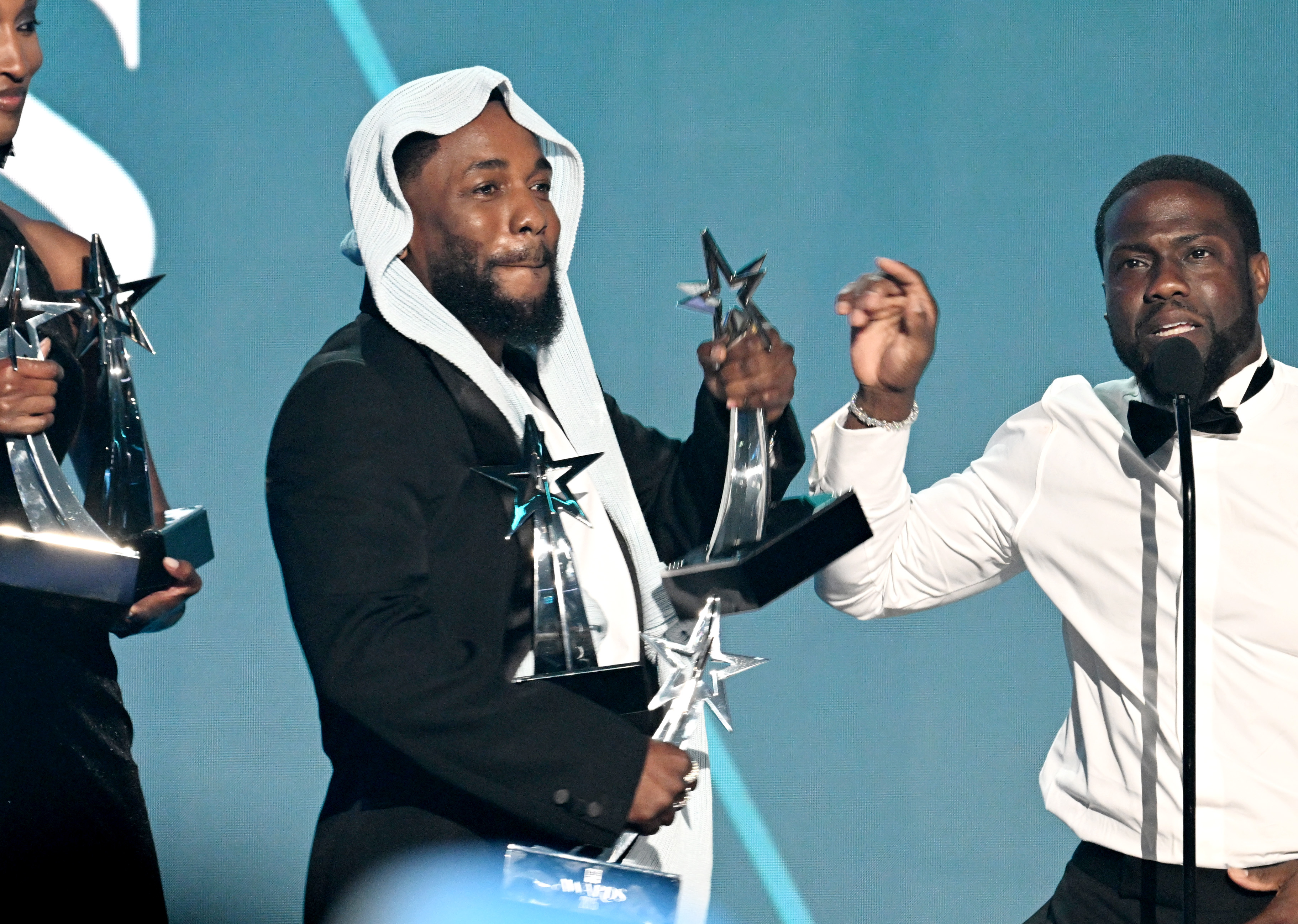 Kendrick Lamar stands alongside comedian Kevin Hart, juggling several of his five BET Awards trophies. The humorous exchange followed Lamar's emotional speech, and unfolded live onstage at the 2025 BET Awards in Los Angeles.