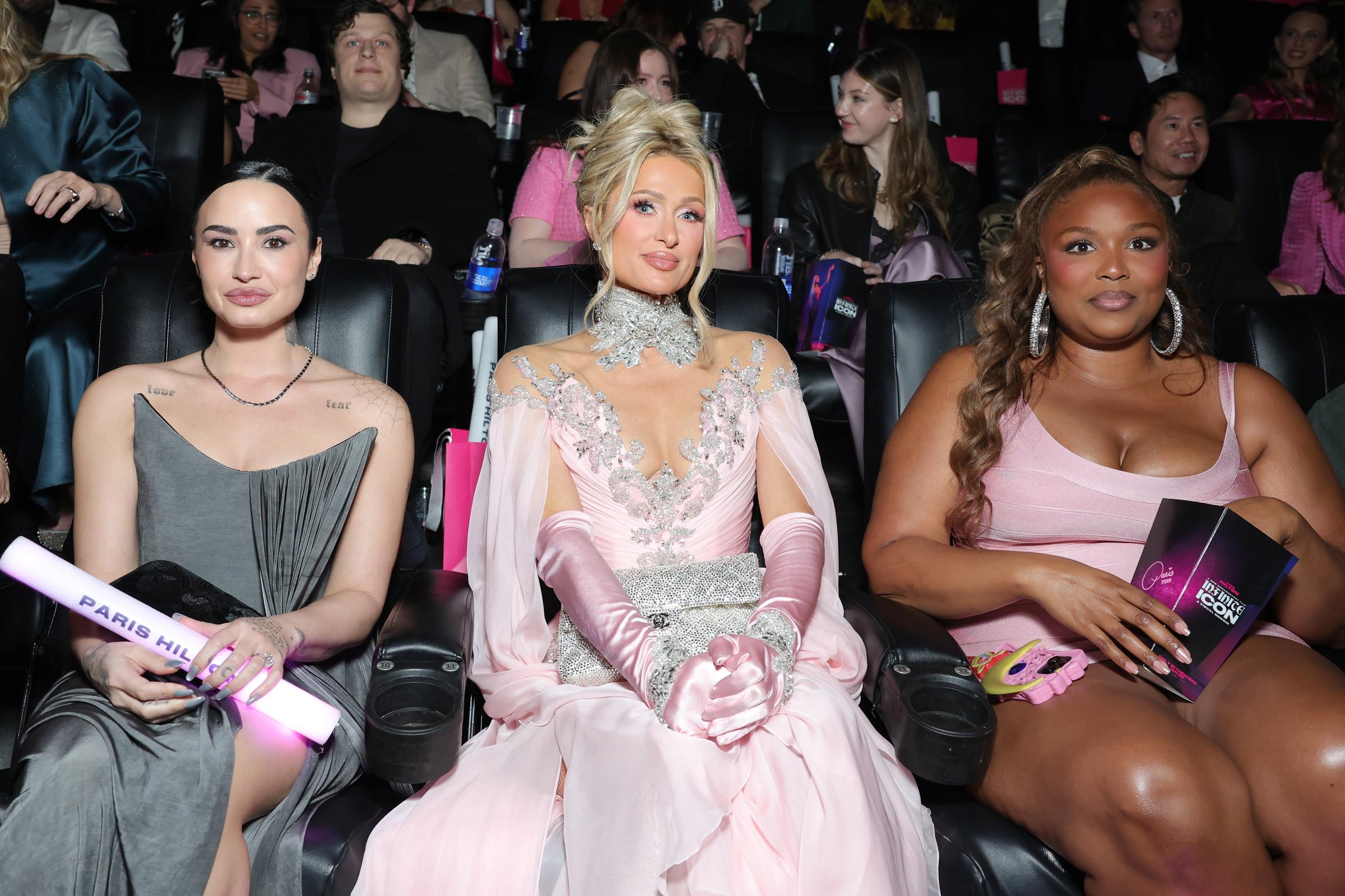 Inside the theater, Lizzo is seated between Paris Hilton and Demi Lovato, with the short dress riding high on her thighs. Her legs, now noticeably leaner, reflect a marked reduction in overall size compared to previous public appearances.