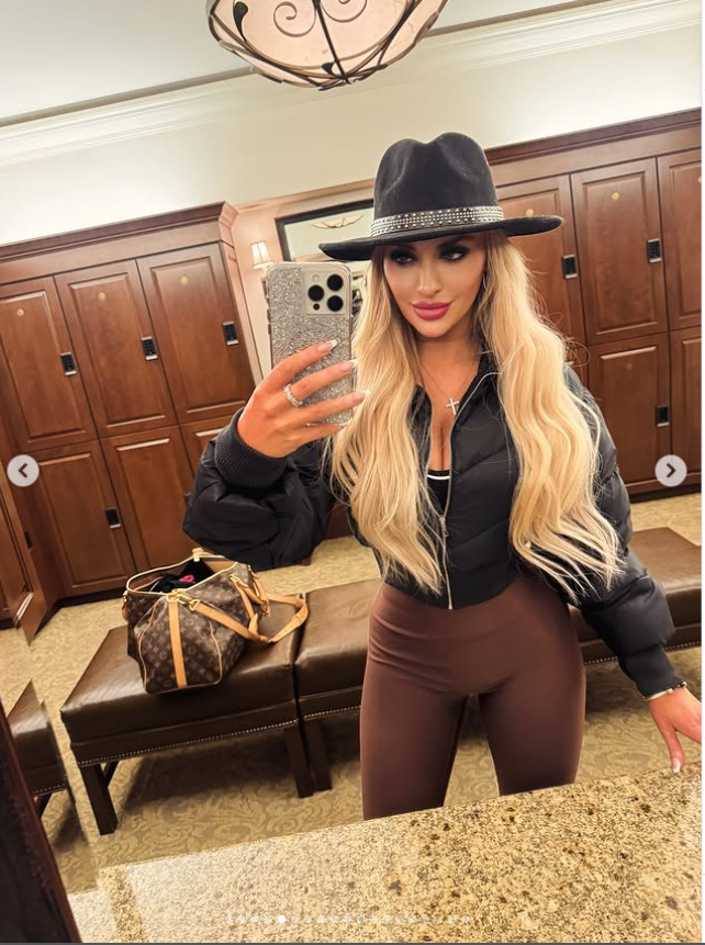 Jennifer Eckhart poses for a mirror selfie in a black cropped jacket, brown leggings and a wide-brimmed hat while holding her phone. | Source: Instagram/jennifereckhart