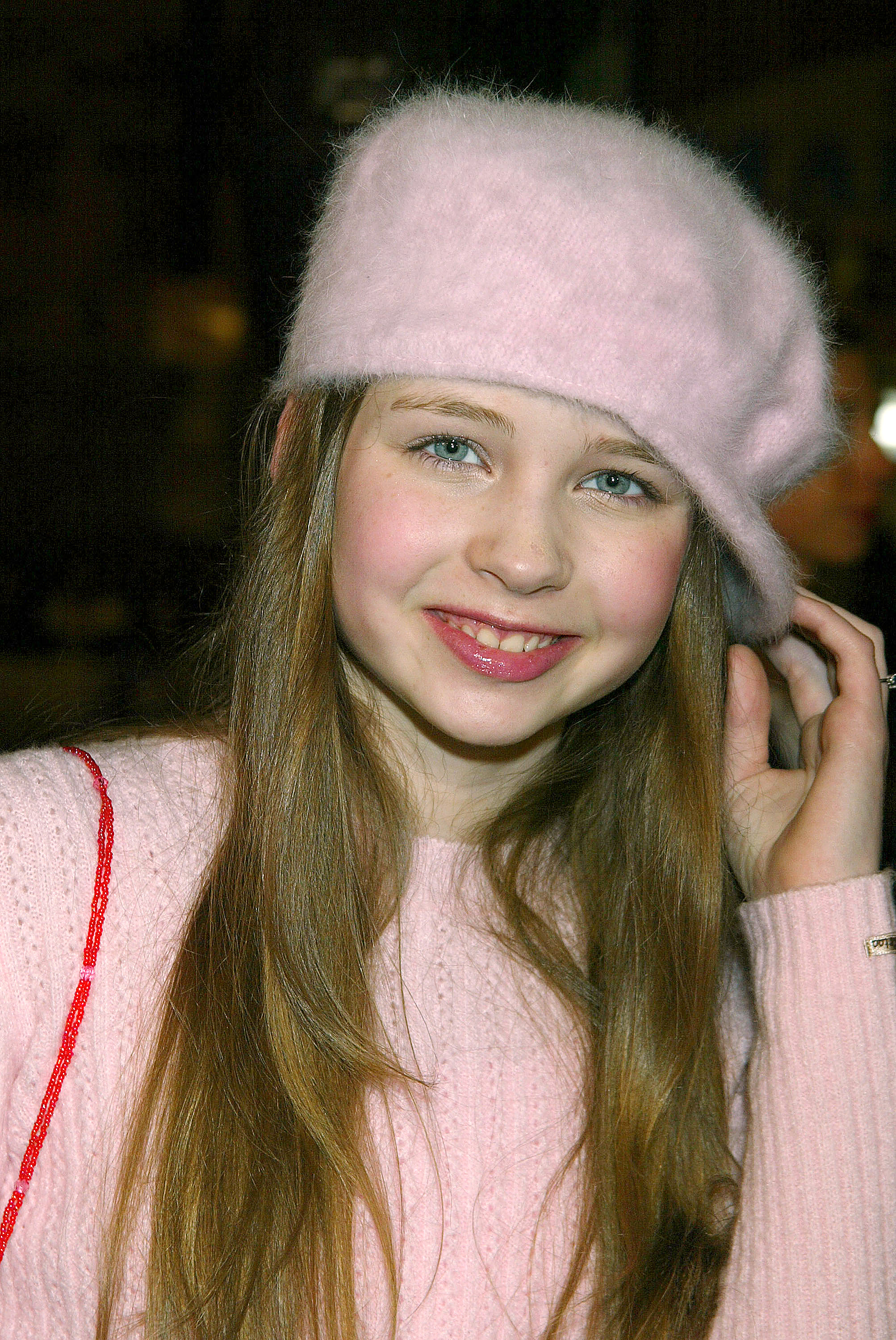 Wearing a pink sweater and matching beret, Daveigh Chase arrives at the premiere of "Along Came Polly" at Grauman's Chinese Theatre during the height of her early Hollywood success. | Source: Getty Images