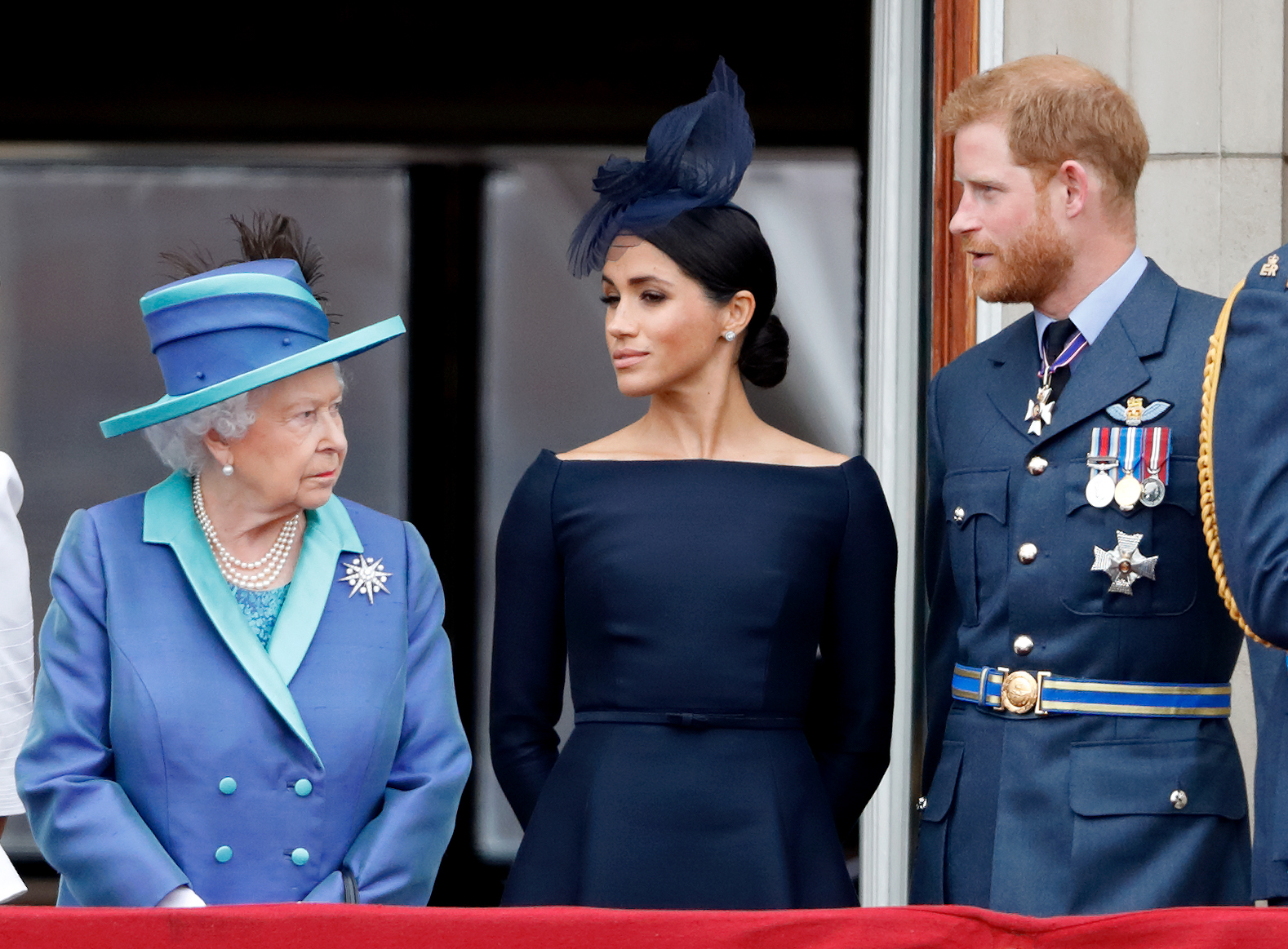 Queen Elizabeth II, Meghan Markle, and Prince Harry watch a flypast to mark the centenary of the Royal Air Force from the balcony of Buckingham Palace on July 10, 2018, in London, England | Source: Getty Images