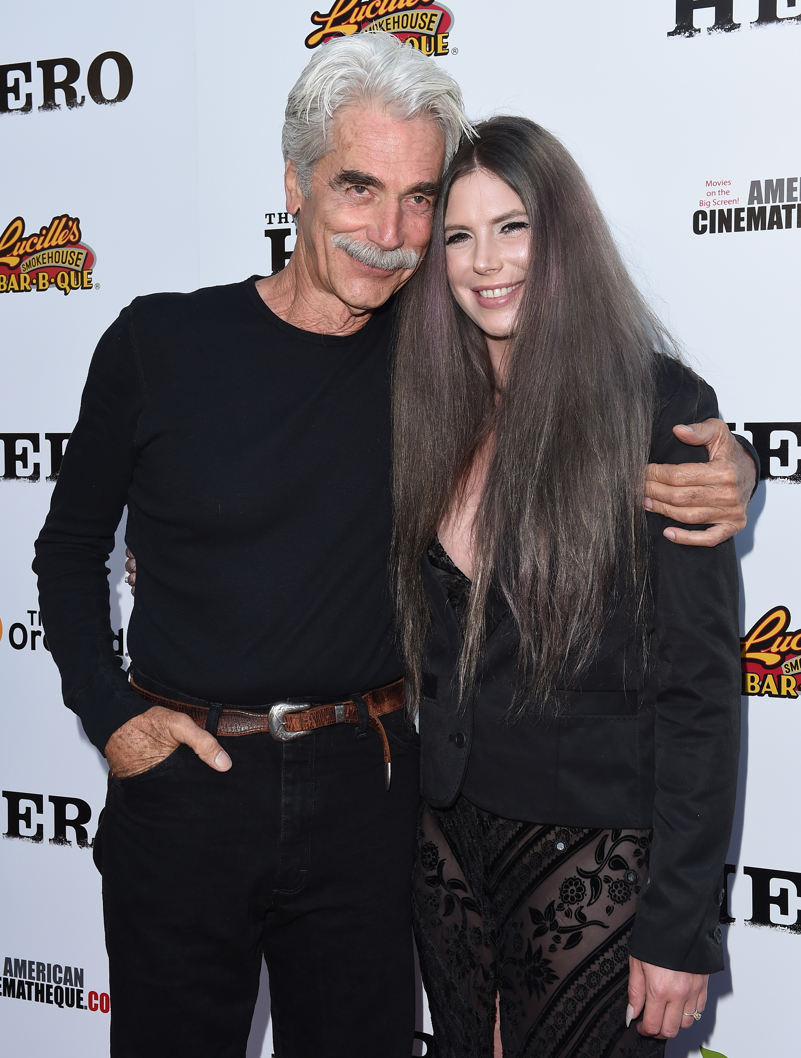 Sam Elliott wrapped an affectionate arm around daughter Cleo Rose Elliott as they arrived at the Los Angeles premiere of "The Hero" at the Egyptian Theatre on June 5, 2017, in Hollywood, California. The stylish duo coordinated in sleek, all-black ensembles, with the veteran actor sporting a simple black long-sleeve crewneck, jeans, and a classic leather belt, while Cleo showcased an edgy tailored blazer over an intricate lace look, complemented by her long, flowing brunette hair. | Source: Getty Images