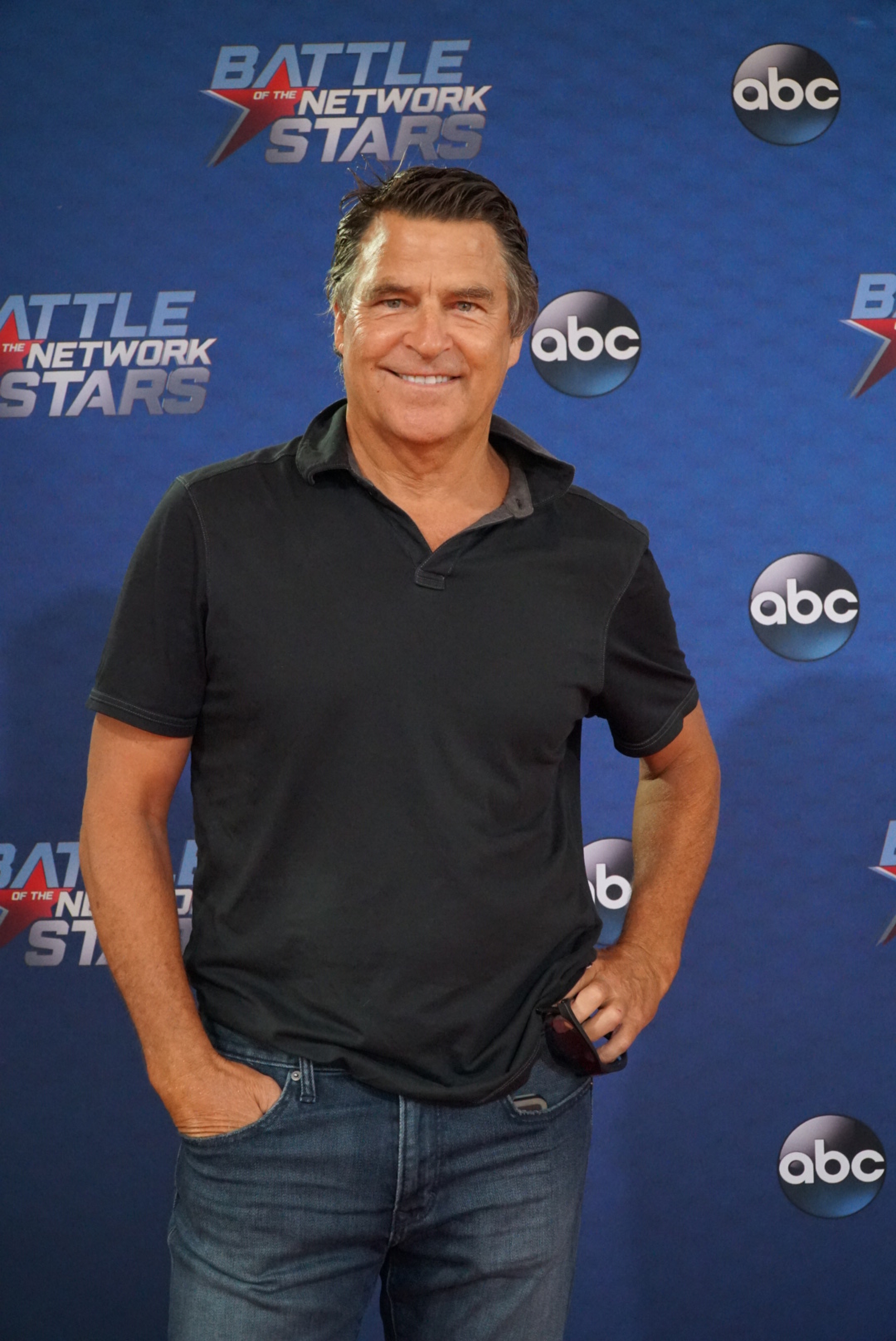 Ted McGinley smiled on the red carpet during the taping of the revival of "Battle of the Network Stars" for the episode "TV Moms & Dads vs. TV Kids," which aired on August 3, 2017, on ABC. The sitcom veteran kept things casually sporty in front of the event backdrop, wearing a charcoal-black polo shirt paired with classic blue denim jeans with one hand resting comfortably in his pocket. | Source: Getty Images