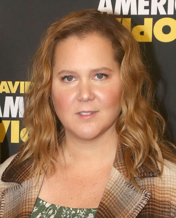 Amy Schumer poses for a photo at the reopening night of "American Utopia" on Broadway in New York City. She wears a patterned coat and styles her hair in soft, loose waves.