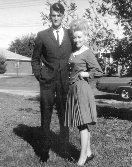Dean and Parton posed outdoors together in another photograph documenting the early years of their decades-long relationship. Dressed formally in a suit and tie, Dean stood beside Parton, who wore a buttoned top and pleated skirt. Images like this became particularly notable because Dean spent most of their marriage outside the public eye, a decision Parton said she respected throughout their life together. | Source: Facebook/One Country