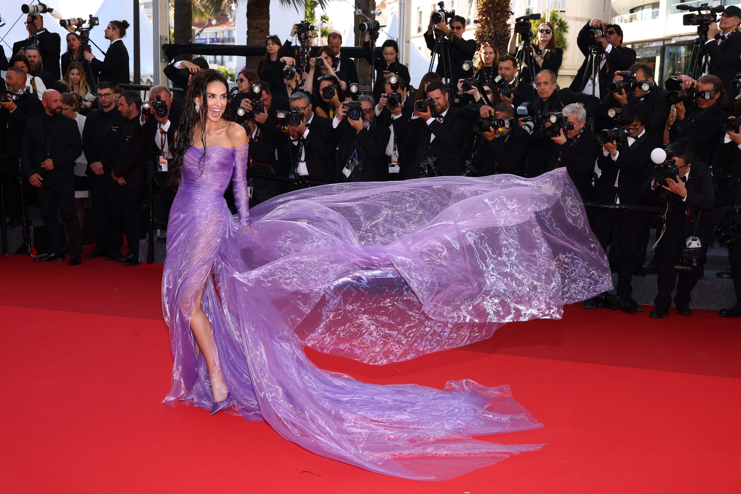 Demi Moore walks the red carpet as the flowing train of her gown trails behind her | Source: Getty Images
