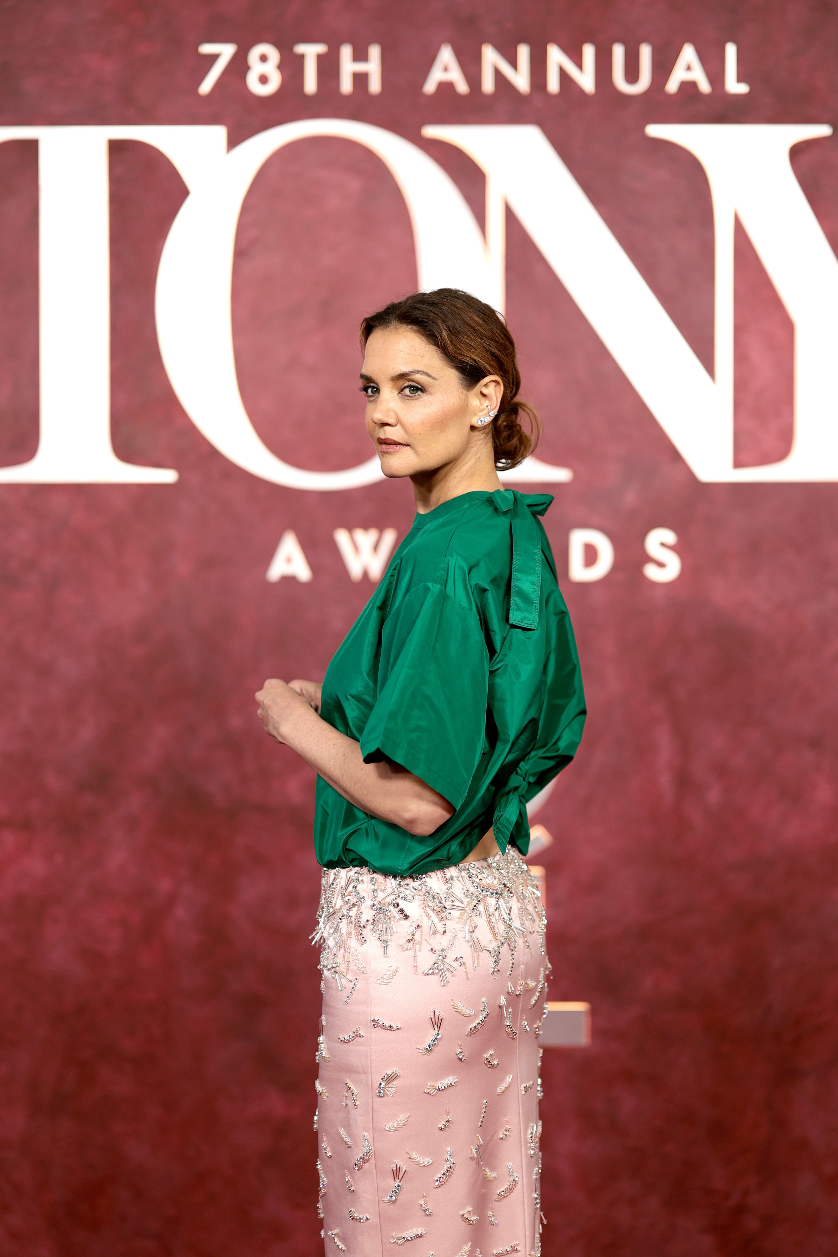 Against the iconic Tony Awards backdrop, Katie Holmes pauses in profile, her bold two-tone look — satin green on top, blush pink and silver beadwork below — firmly capturing the attention of fashion watchers and photographers alike.