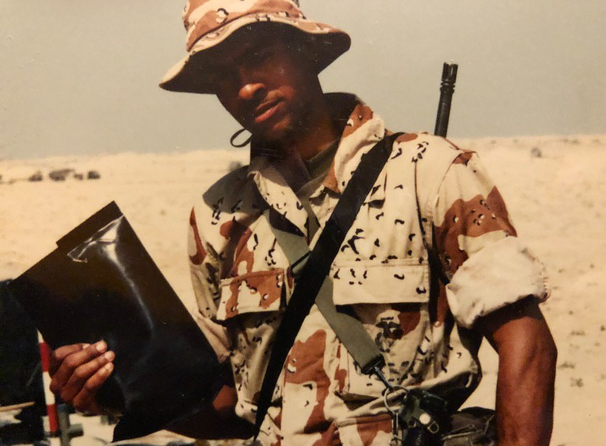 Orville Richard Burrell, known as Shaggy, stands outdoors in desert camouflage, holding a flat black object at his side during his military service | Source: Instagram/direalshaggy