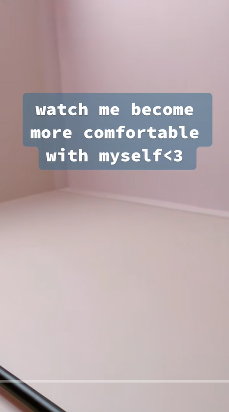 A pale pink room with empty flooring and soft lighting. Centered on the screen is a text overlay introducing the theme of self-comfort and personal change | Source: TikTok/st0nedc0w
