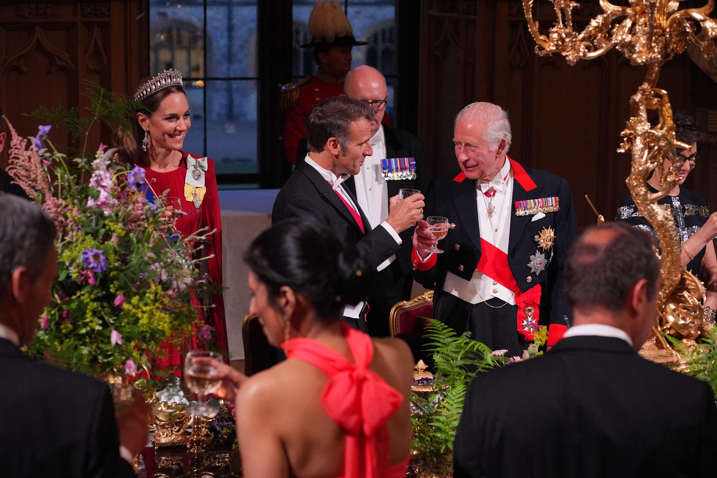 France's President, Emmanuel Macron and King Charles III appear to be in a conversation. Princess Catherine is also seen in the picture frame looking ahead with a smile on her face.