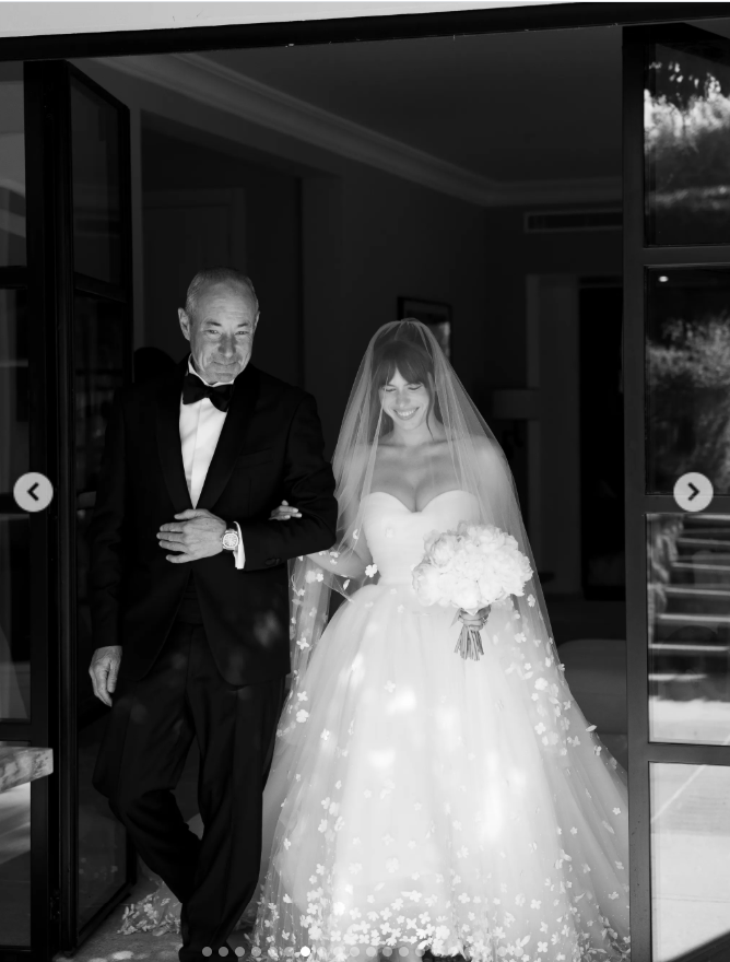 Paula Bruss-Lee stepped out arm in arm with her father, smiling beneath her flower-dotted veil as she made her way toward the ceremony. | Source: Instagram/thierryjoubertphotography