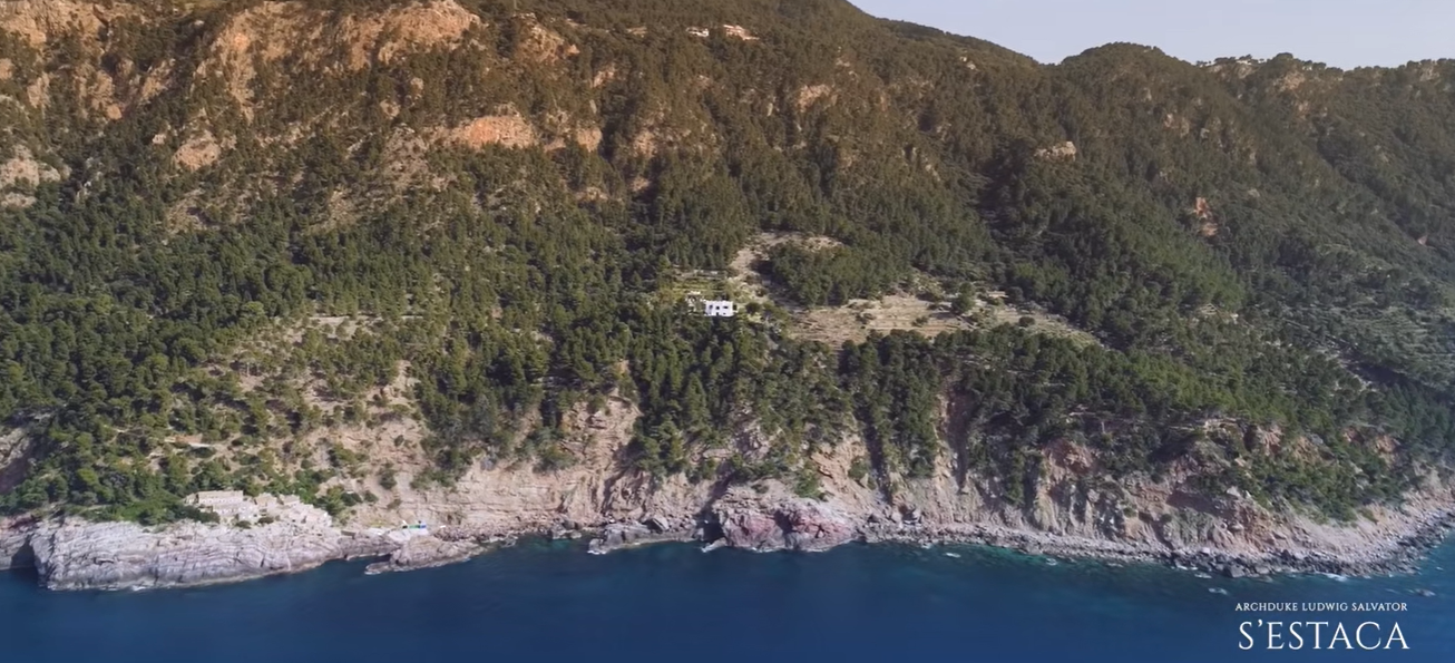 S'Estaca almost disappears into the forested hillside when seen from the water. The steep coastline and thick trees show just how private the sprawling Mallorca estate can feel. | Source: YouTube/billionsluxuryportal