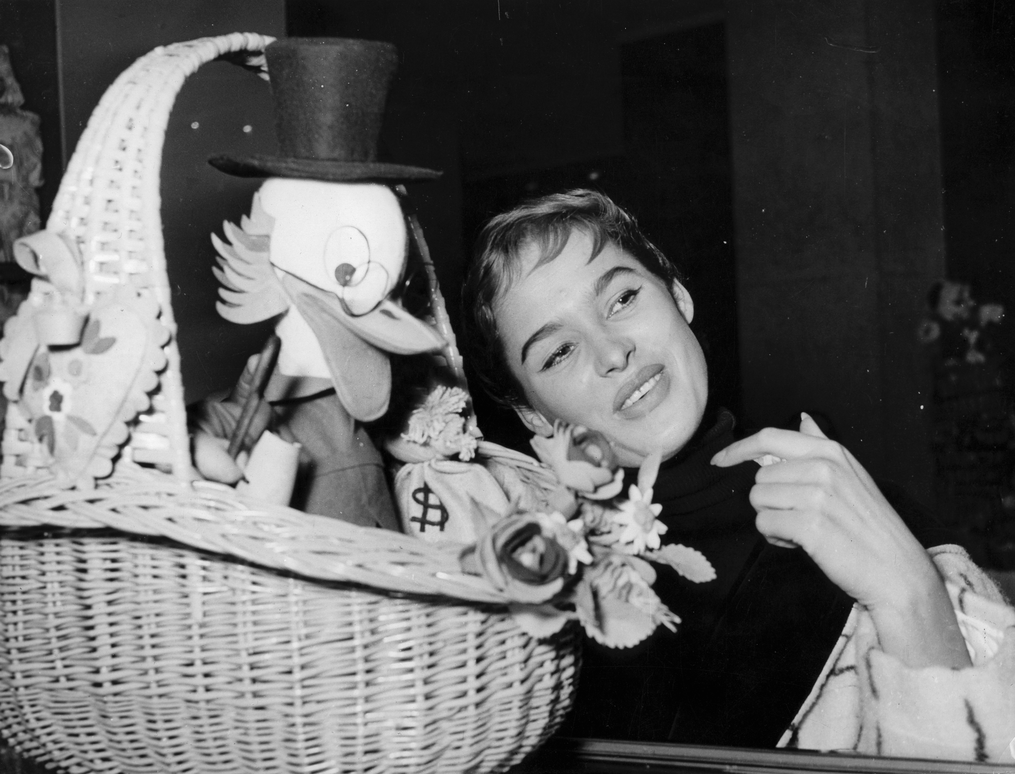 The celebrity pictured with a figure of Scrooge McDuck in a basket on January 1, 1956, in Switzerland. | Source: Getty Images