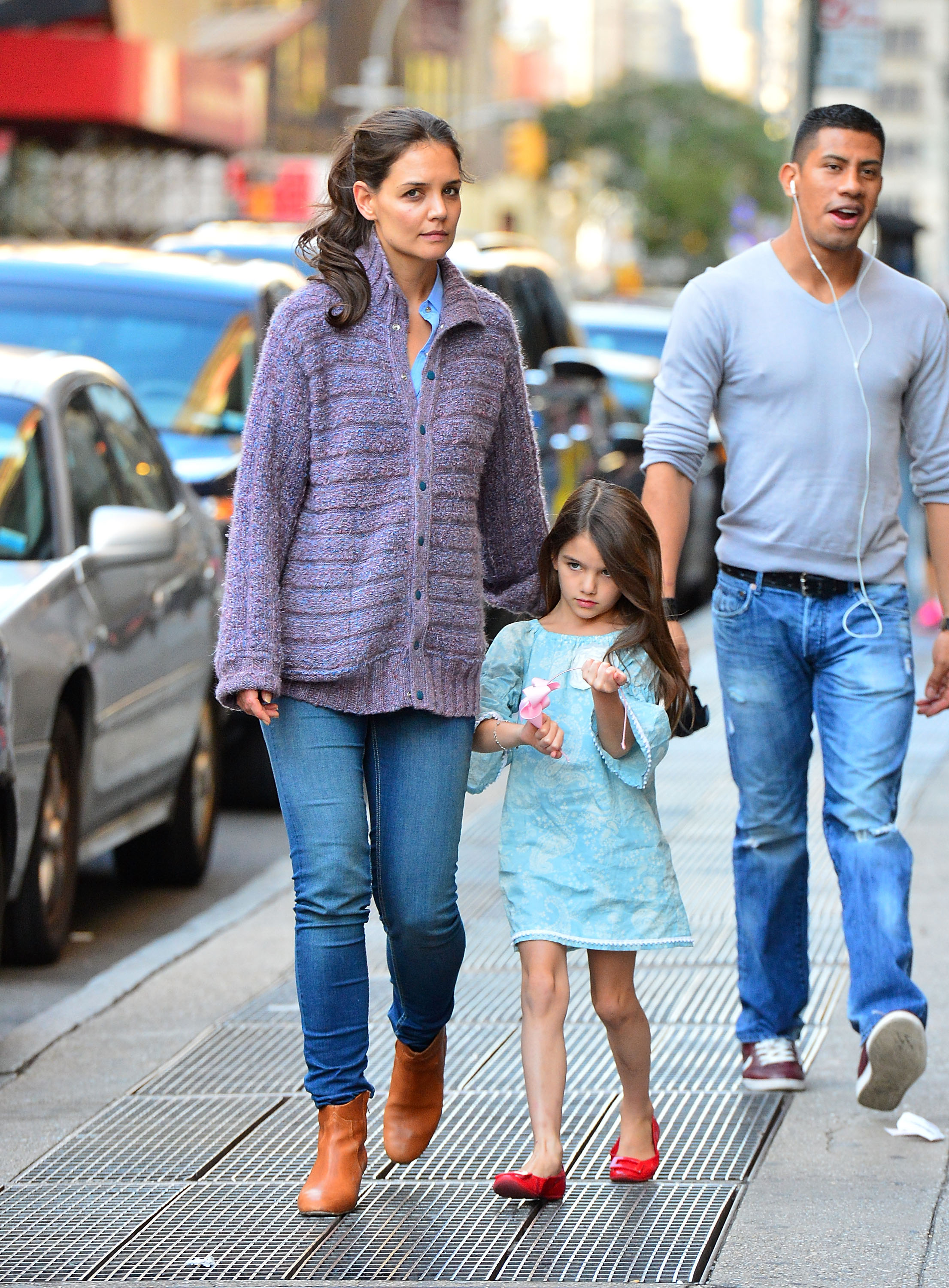 Katie Holmes is pictured walking down the street with Suri Cruise nestled close by her side. As they move through the crowd, Katie’s hand rests gently behind her daughter’s back — a subtle, protective gesture that speaks volumes.