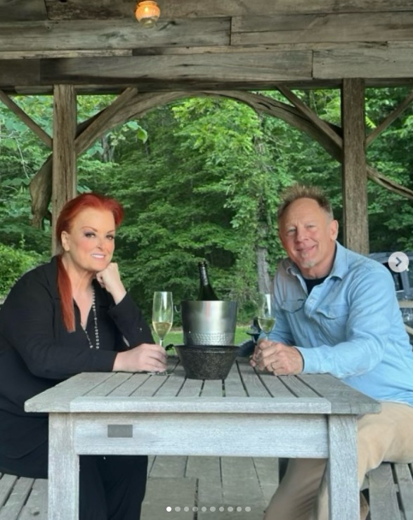 Wynonna and Cactus enjoy a moment together beneath the wooden gazebo, with leafy trees surrounding the structure. The photograph offers a closer look at one of the property's outdoor gathering spots. | Source: Instagram/wynonnajudd