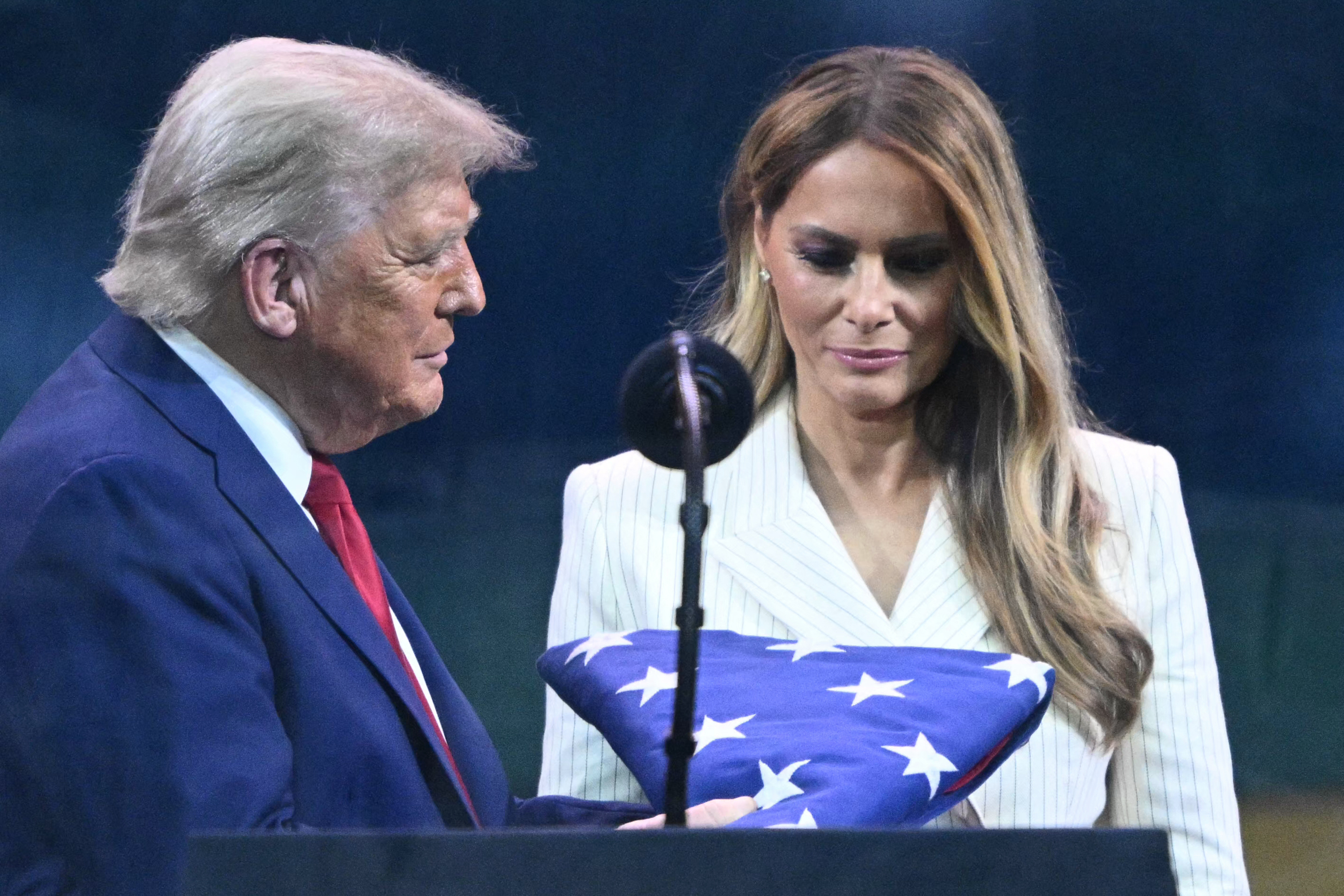 Donald and Melania Trump look at a U.S. flag handed to Trump by a member of the Army's Golden Knights on June 14, 2025 | Source: Getty Images