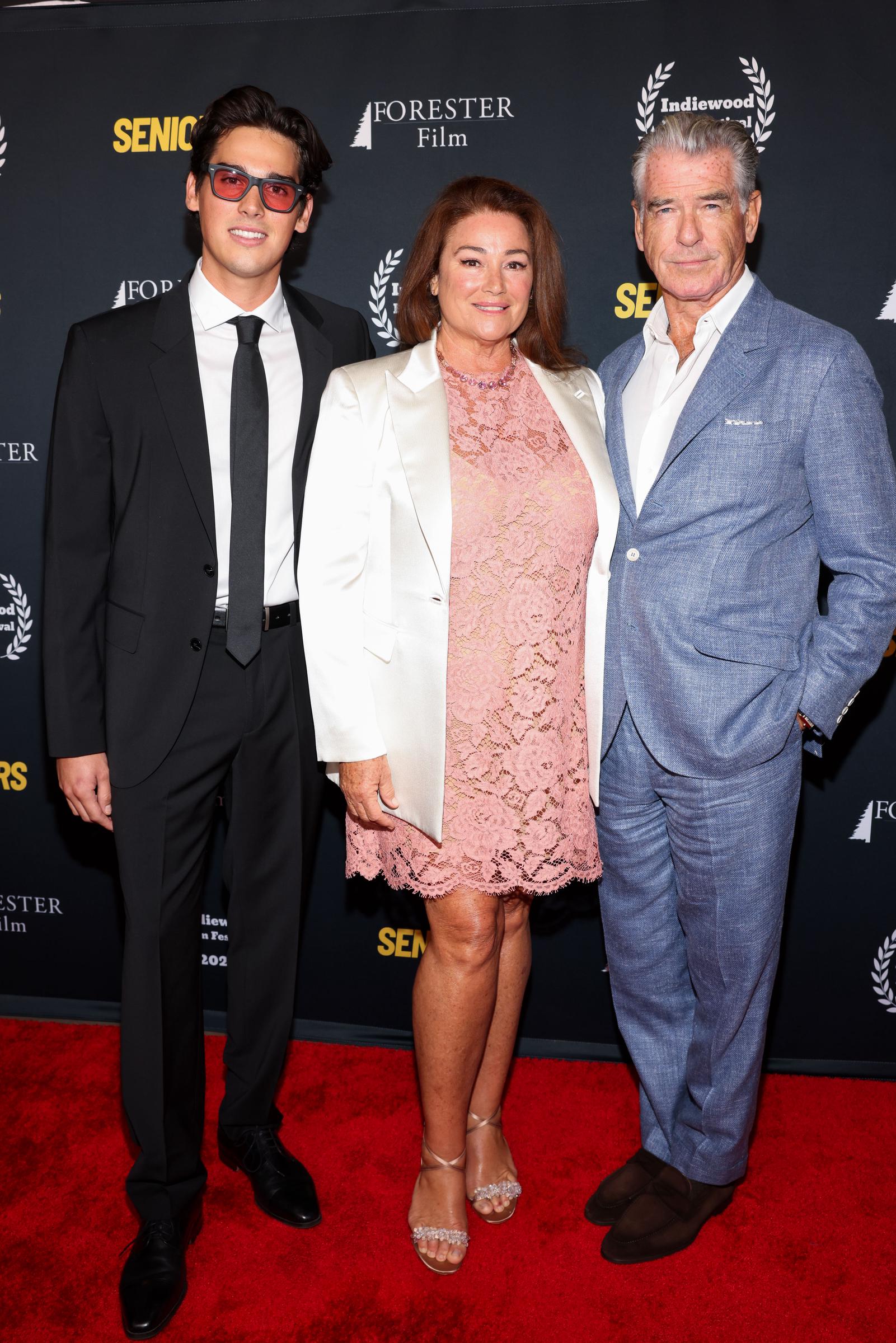 Pierce Brosnan and Keely Shaye Smith posed proudly with their son Paris, with Keely wearing a pink lace dress and Pierce a light blue suit, highlighting the family's close bond. | Source: Getty Images.