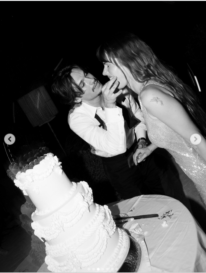 In a playful black-and-white moment, Dylan fed Paula a bite of wedding cake as the couple leaned toward each other beside the towering, elaborately decorated confection. | Source: Instagram/dylanjaggerlee