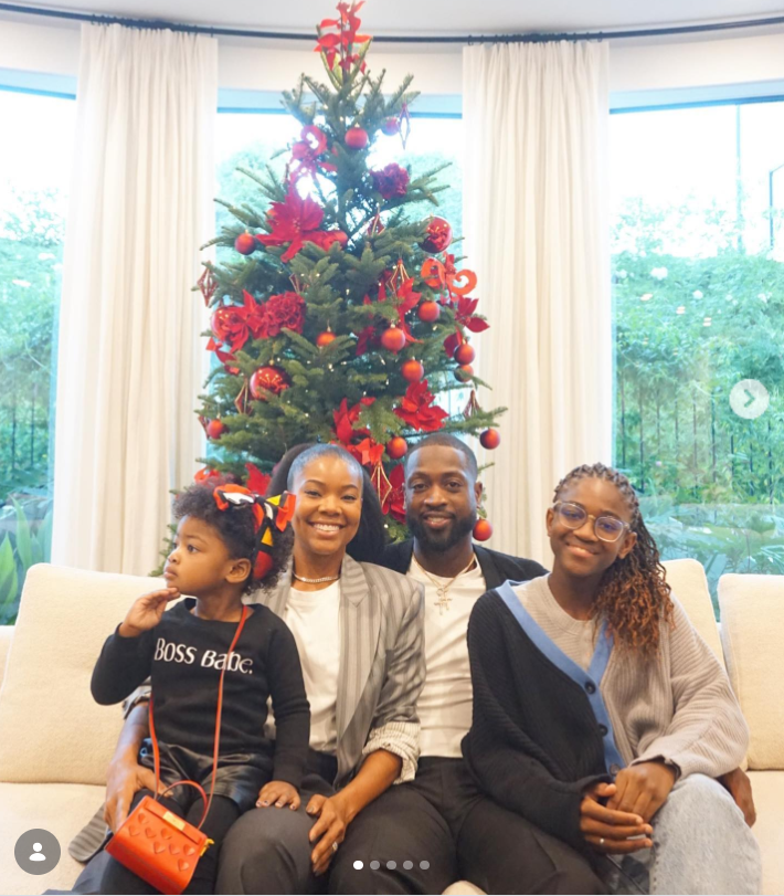 A cozy family portrait shows Gabrielle Union and Dwyane Wade seated on a couch with their children in front of a decorated Christmas tree. | Source: Instagram/gabunion