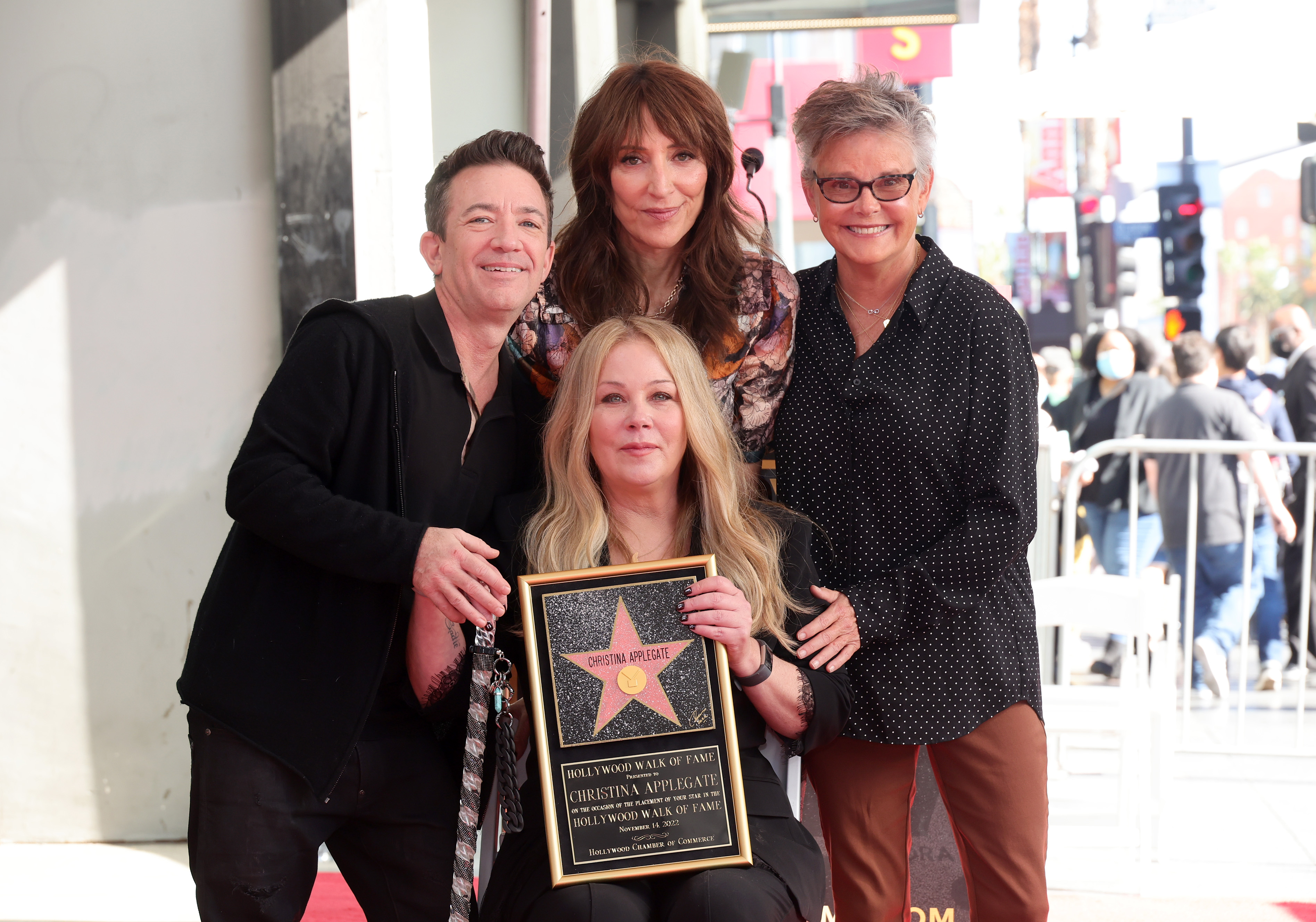 David Faustino, Katey Sagal, and Amanda Bearse gathered around Christina Applegate to celebrate her star ceremony on the Hollywood Walk of Fame on November 14, 2022, in Los Angeles, California. The "Married... with Children" cast members shared an affectionate, supportive reunion as Applegate proudly held her framed Walk of Fame star plaque, flanked by Faustino in an all-black look, Sagal in a patterned blouse, and Bearse smiling warmly in a black polka-dot button-down shirt and glasses. | Source: Getty Images