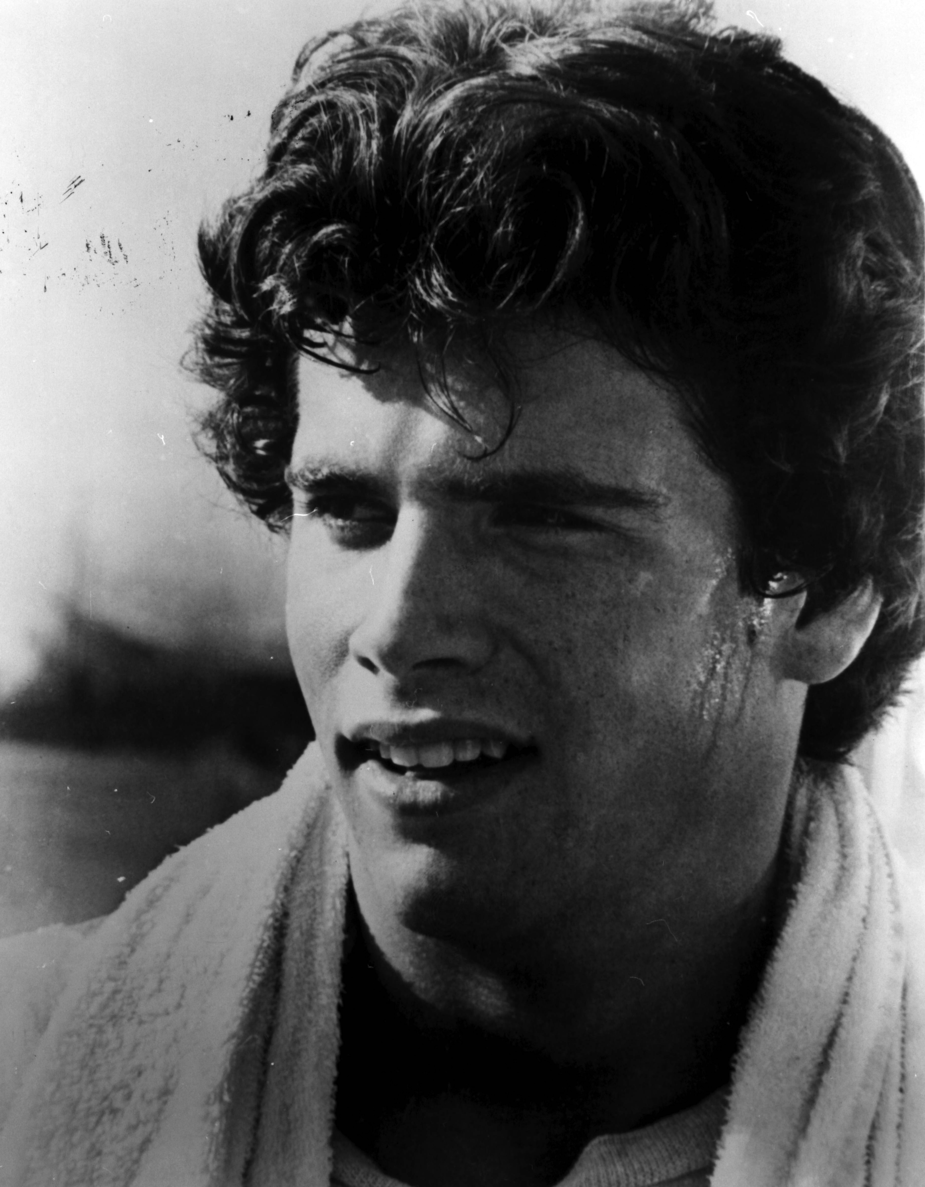 The future heartthrob showcases his classic good looks in a brooding black-and-white portrait from the 1970s. With sweat glistening along his temple and jawline, he gazes thoughtfully to the side with thick, wavy dark hair and a white terrycloth towel draped around his neck. | Source: Getty Images