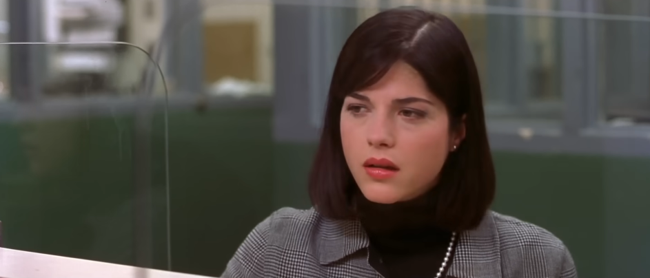 Selma Blair appears in character as Vivian Kensington in a scene from the 2001 film "Legally Blonde". Looking on with a subdued and attentive expression, she wears a black turtleneck under a grey Glen plaid jacket, accessorized with a pearl strand necklace, small stud earrings, and a sleek shoulder-length brunette bob with side-swept bangs. | Source: YouTube/Amazon MGM Studios