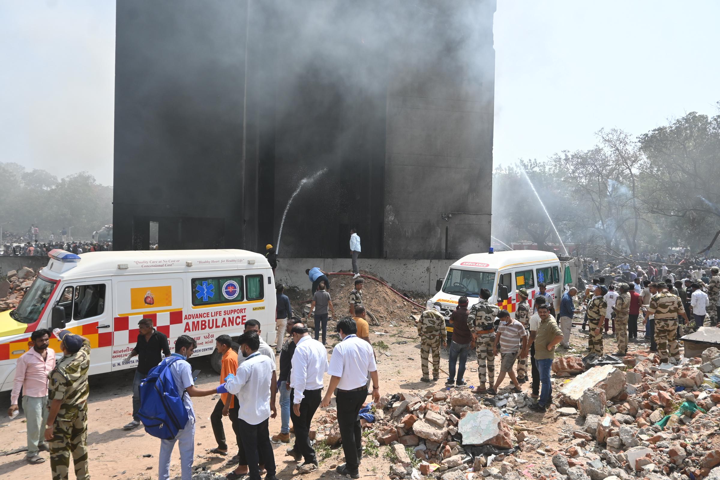 Rescue workers hose down a smoke-filled building as emergency crews and ambulances gather at the crash site. | Source: Getty Images